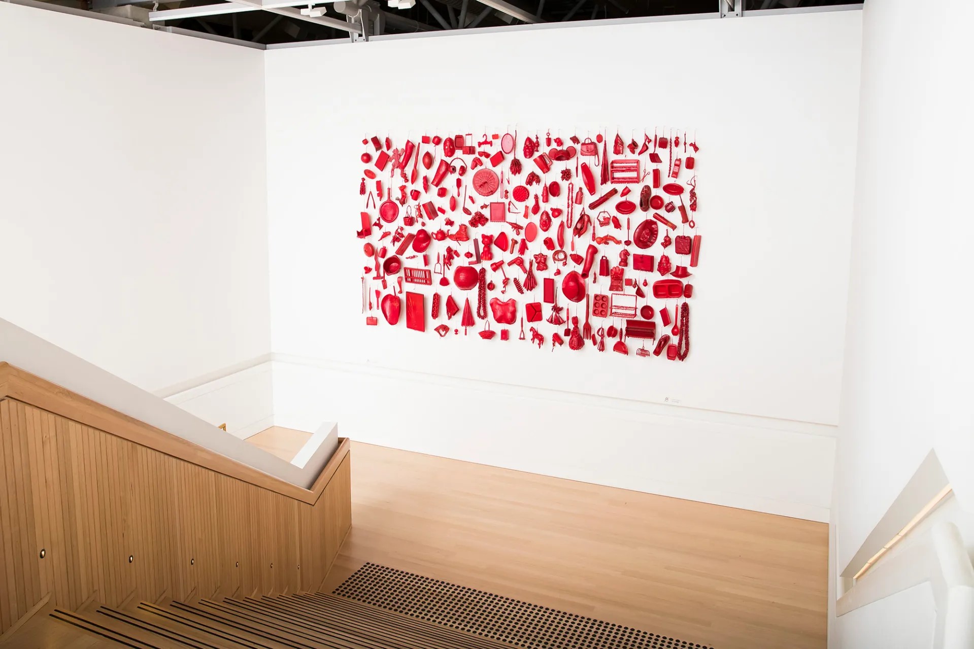 Red dipped objects are hung in a rectangle on a stairway in Te Papa.