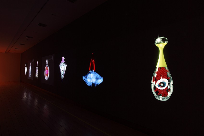 Illuminated animations of crystal flasks on a black background in an art gallery.