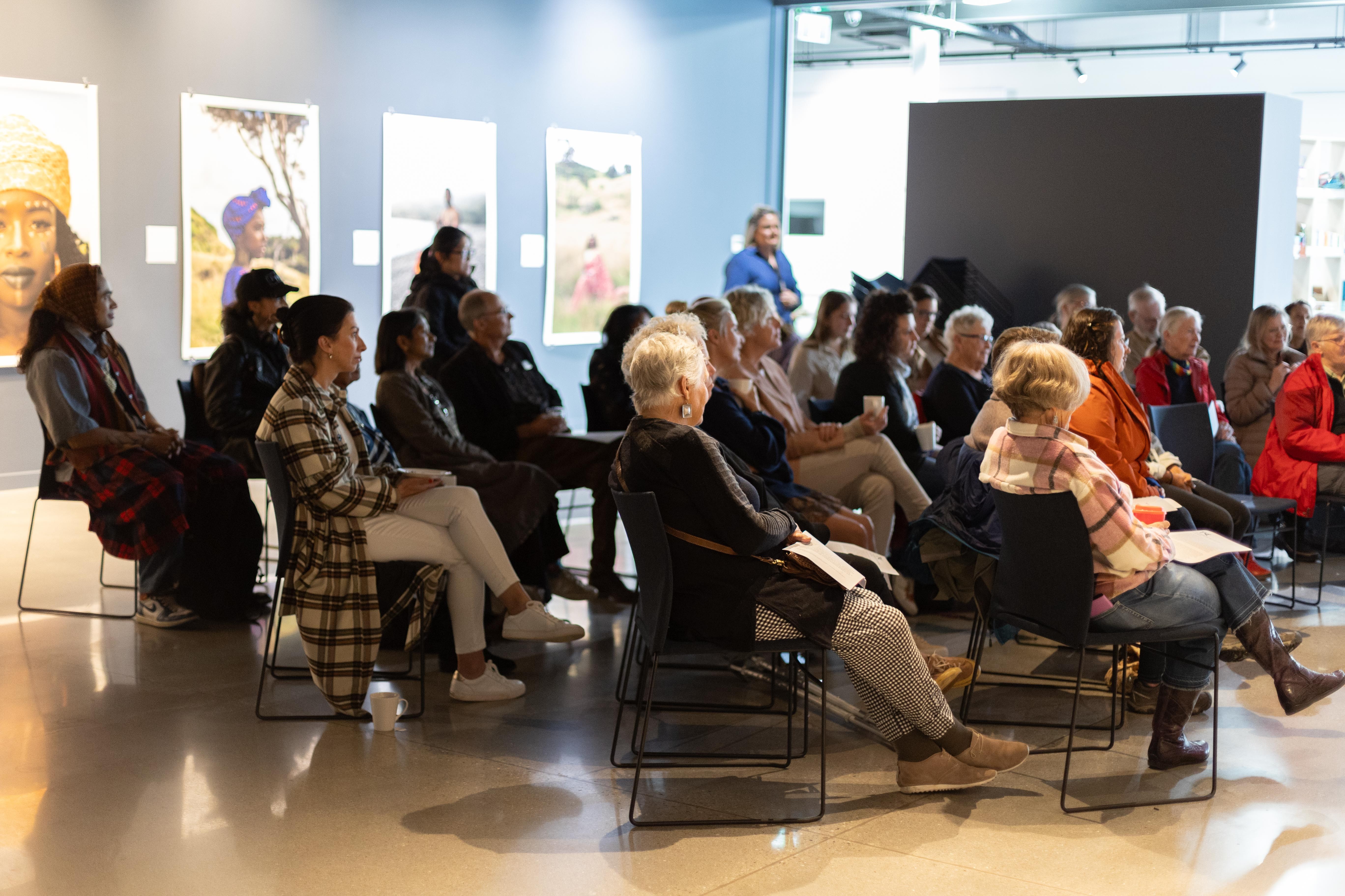 A large group of people sitting in an art gallery