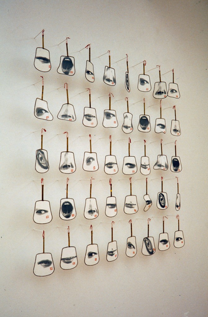 A grid of handheld fans each printed with ann eye, mouth, nose or ear.