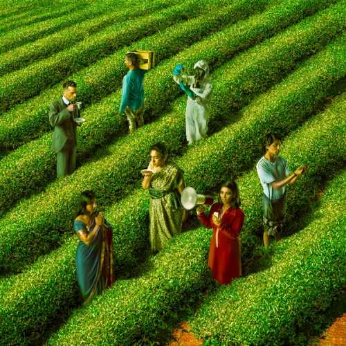 Seven South Asian actors in different garbs and time periods stand in a field of green tea crops, facing various directions.