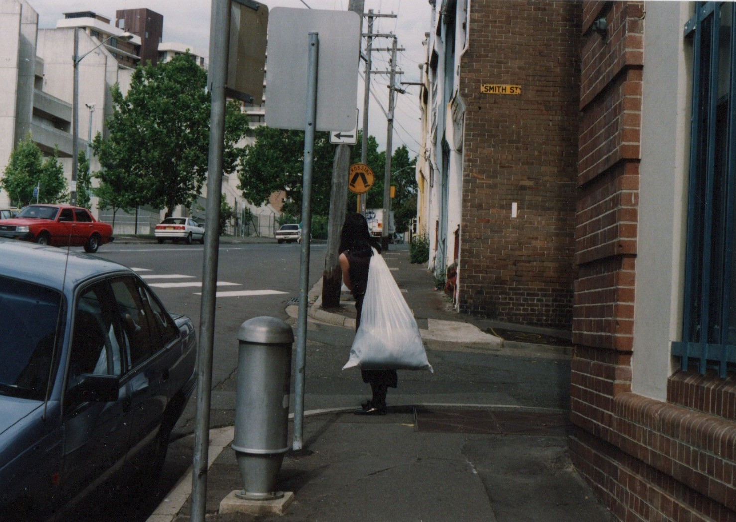 A woman on a street carrying a white bag full of material