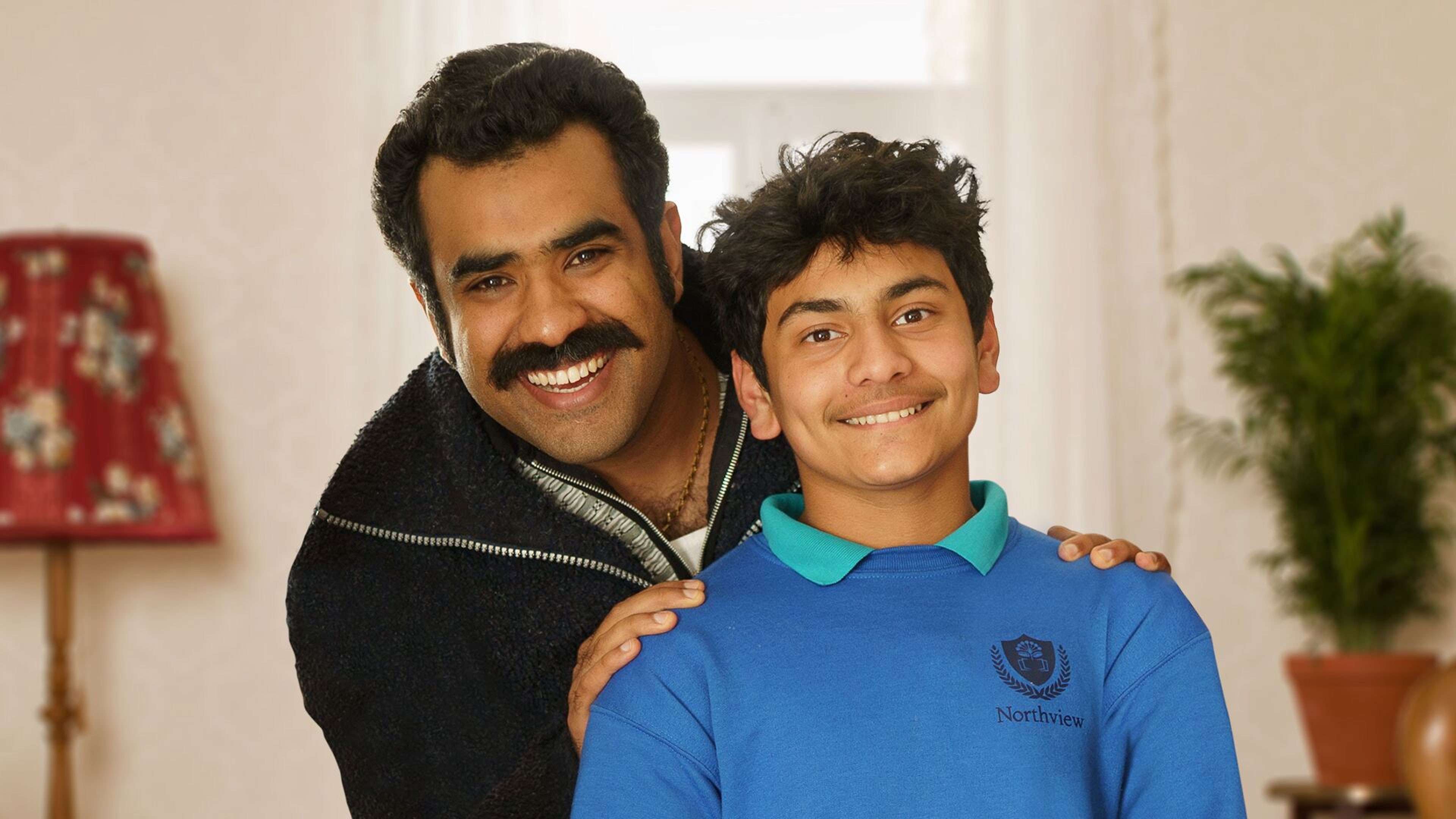 A man and his son grin at the camera in the style of a sitcom