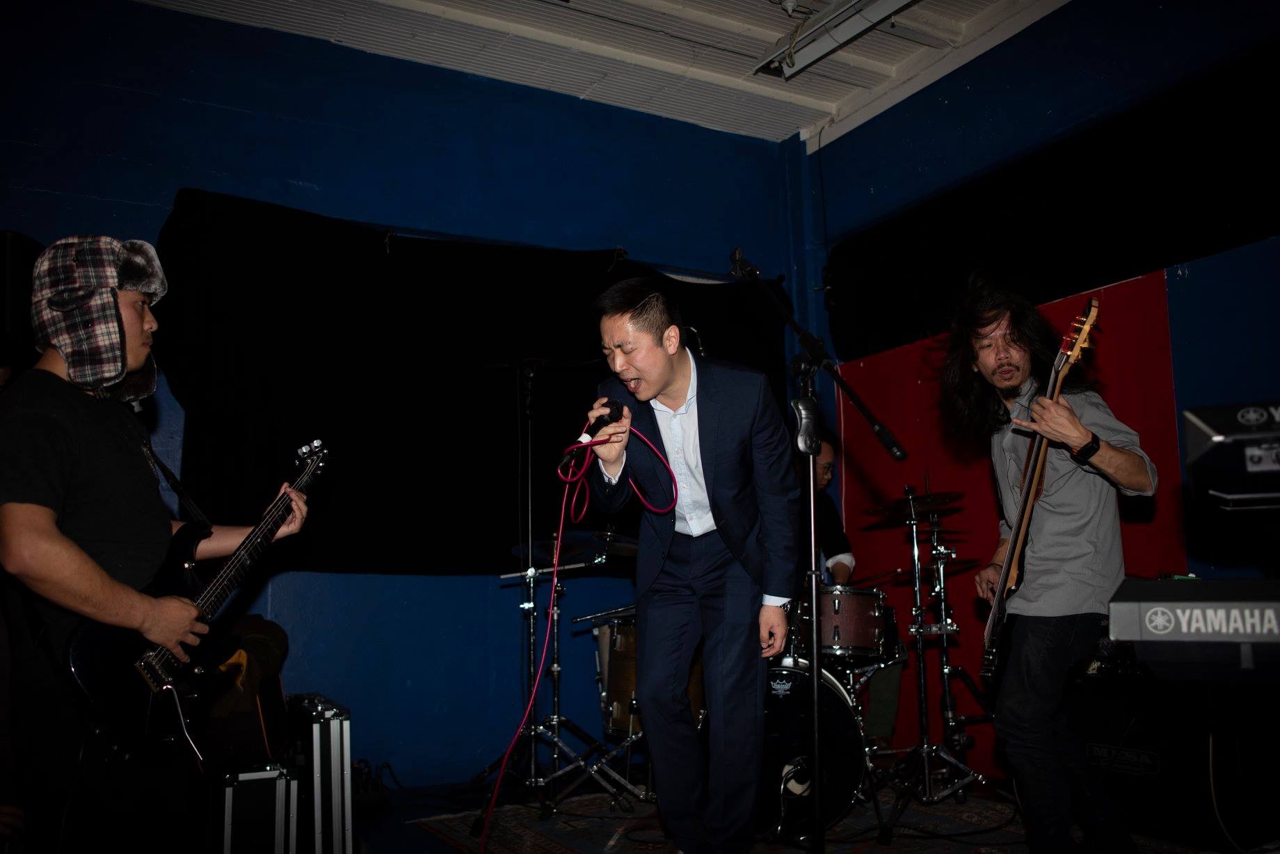 Two guitarists and a singer perform in a small room