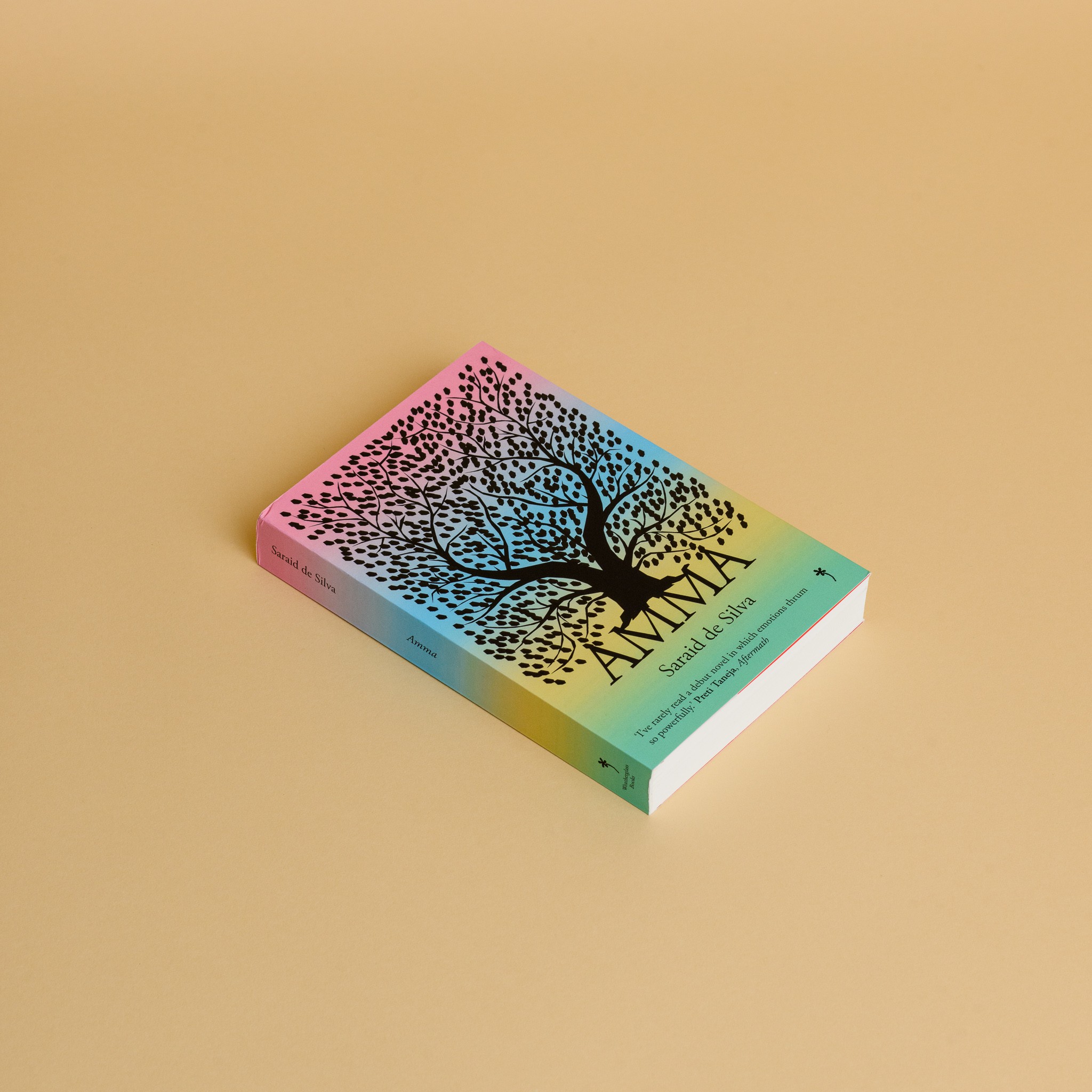 A book featuring a rainbow coloured background with a silhouette of a tree on the front