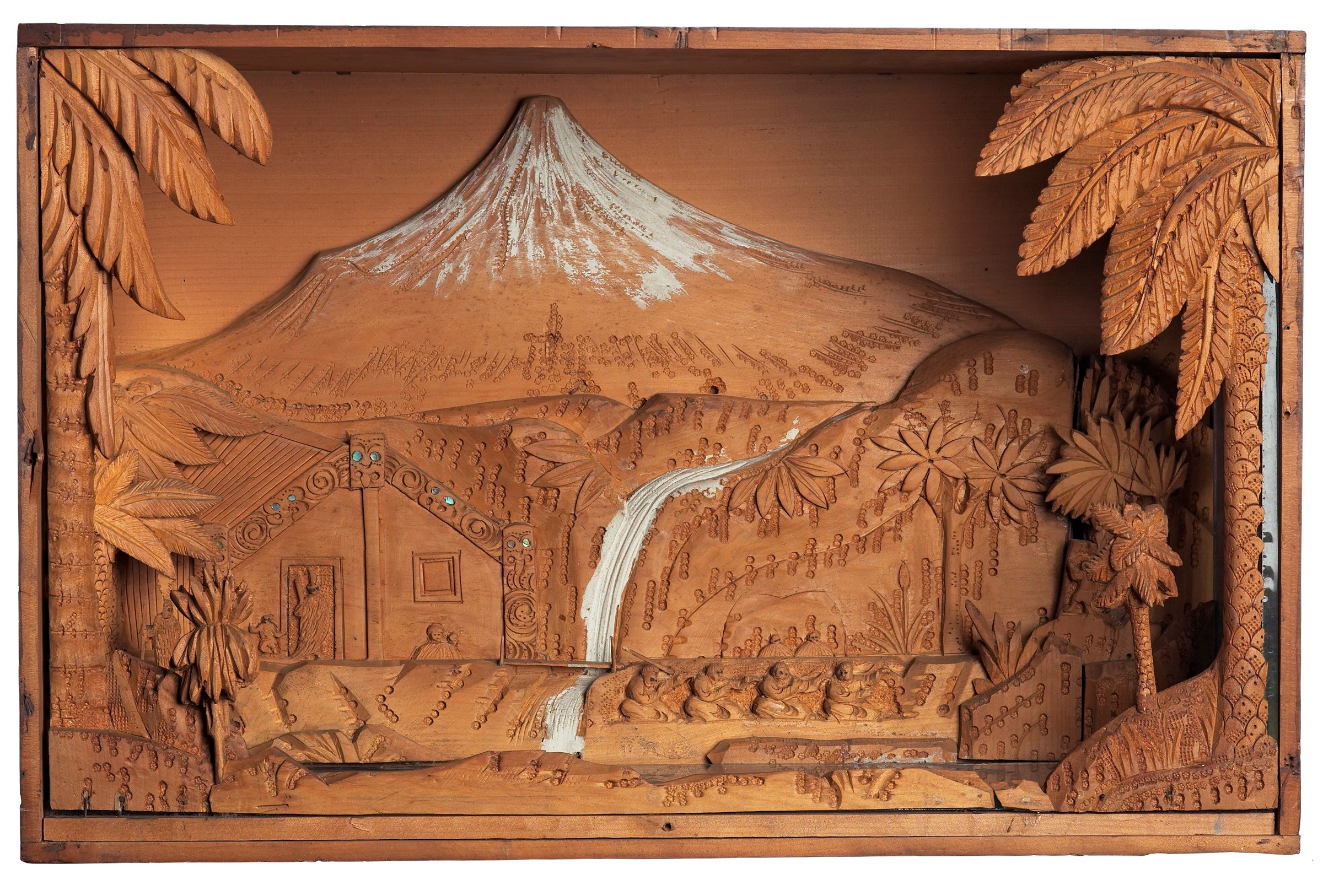 A carved wooden diorama showing Taranaki maunga in the background and a wharenui in the foreground.