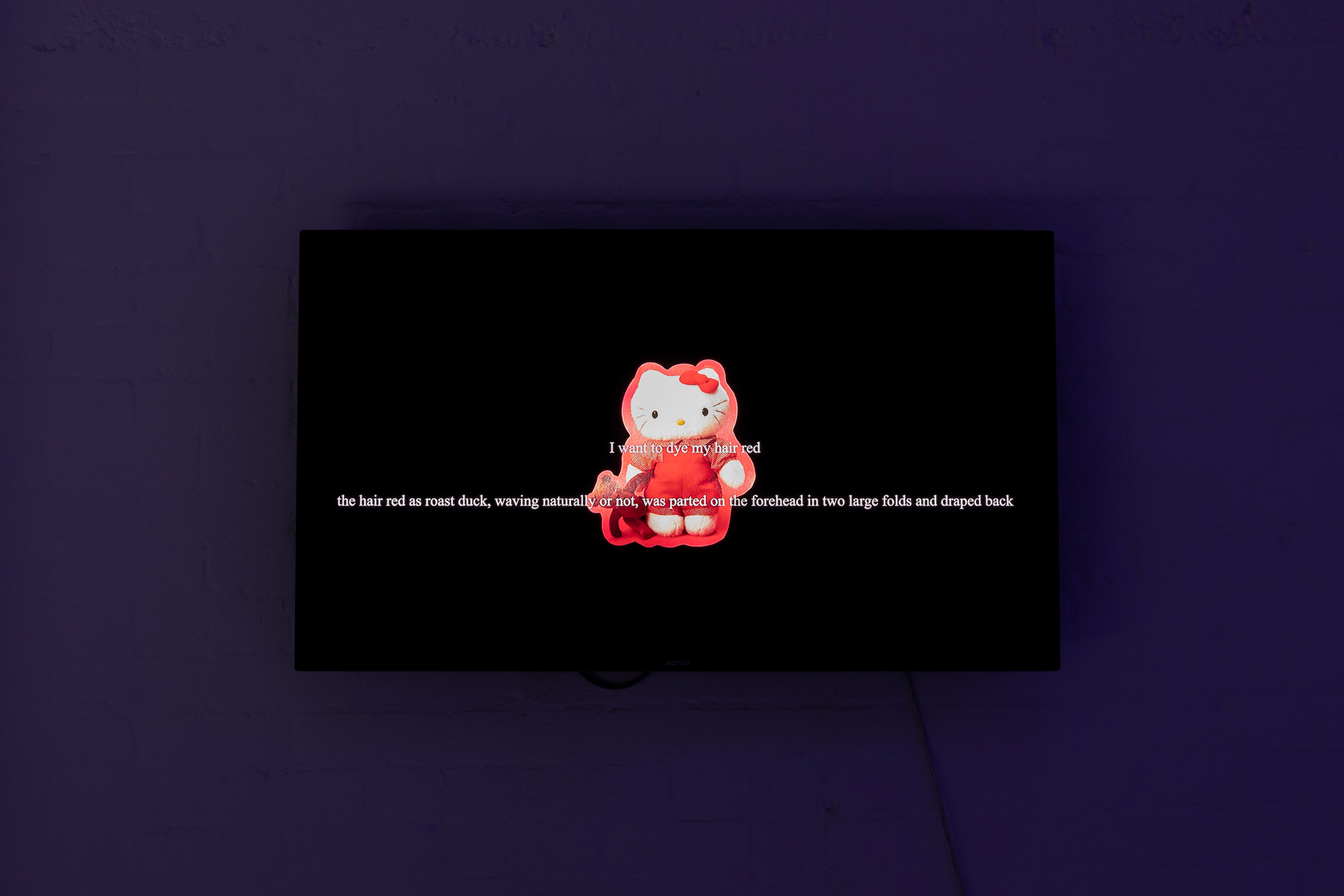 a video on the wall featuring text overlay on a Hello Kitty icon