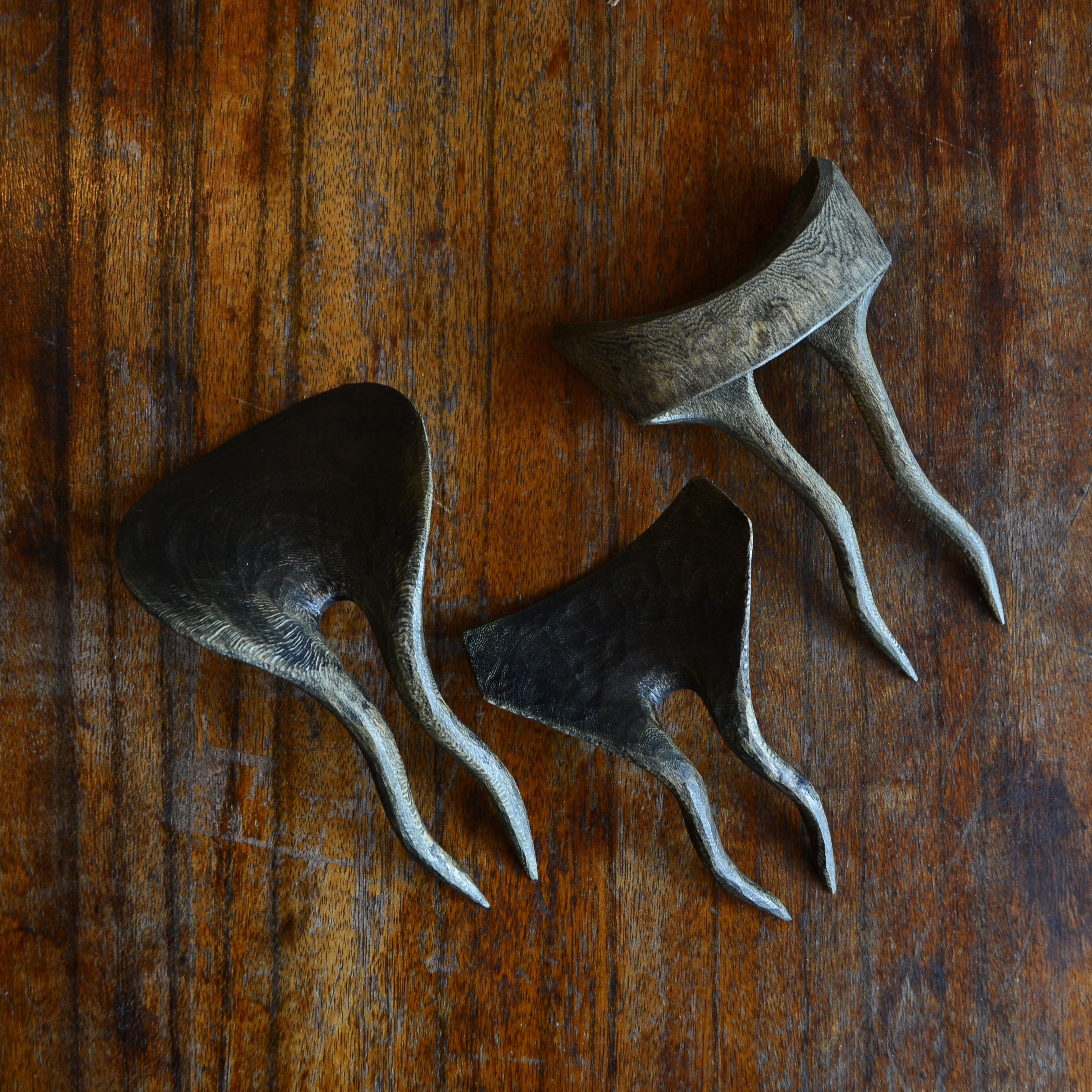 Three wavy shaped two-pronged hairpins carved out of houhere greenwood