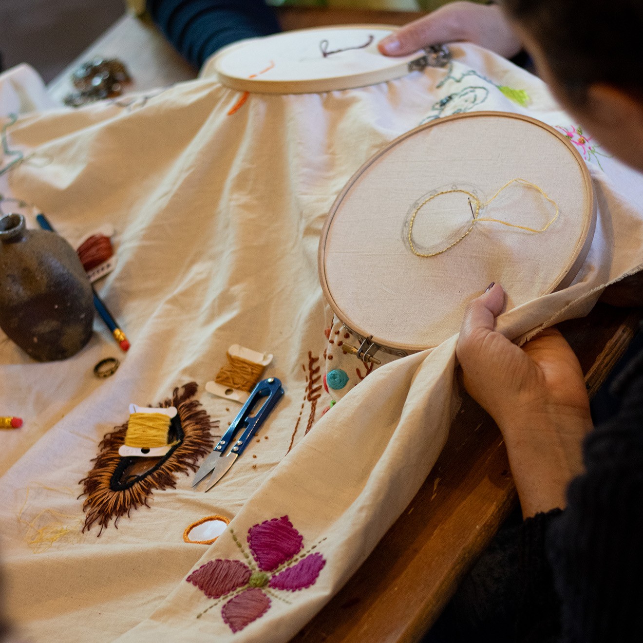 A person sewing a fabric with embroidery