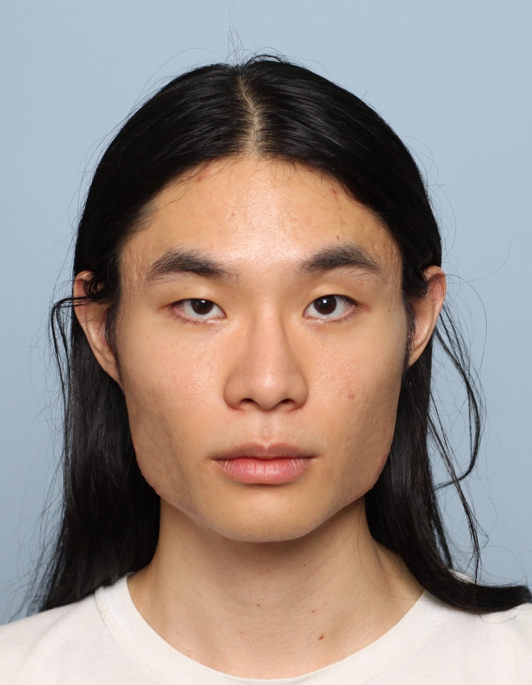 Close-up of a person with shoulder-length hair and a white t-shirt