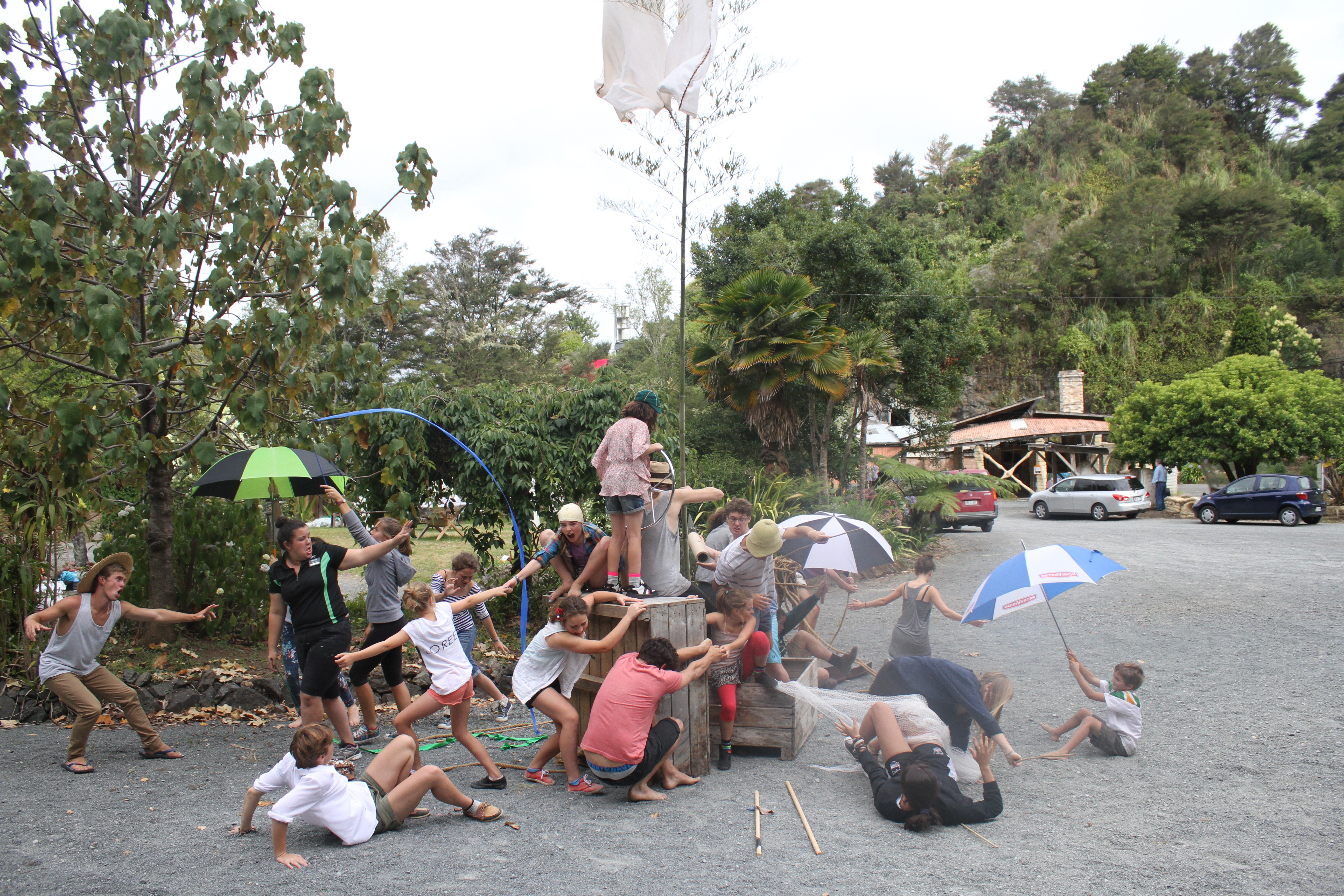 A group of actors around an improvised set made of crates and umbrellas.