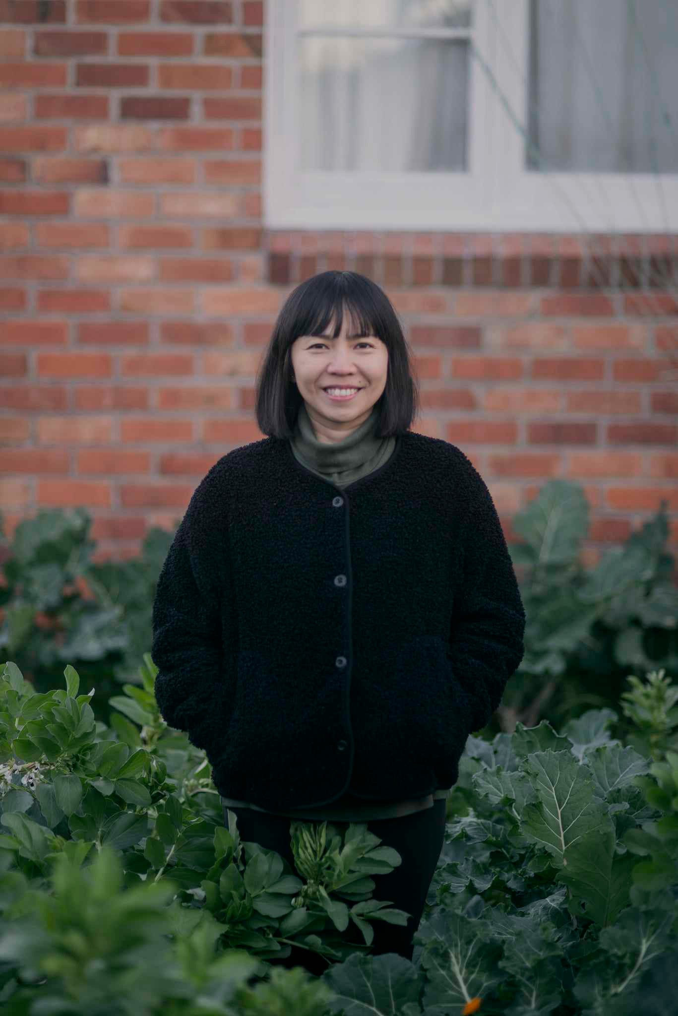 Person of Filipino descent with a bob cut and wearing an oversized dress standing in a lush garden