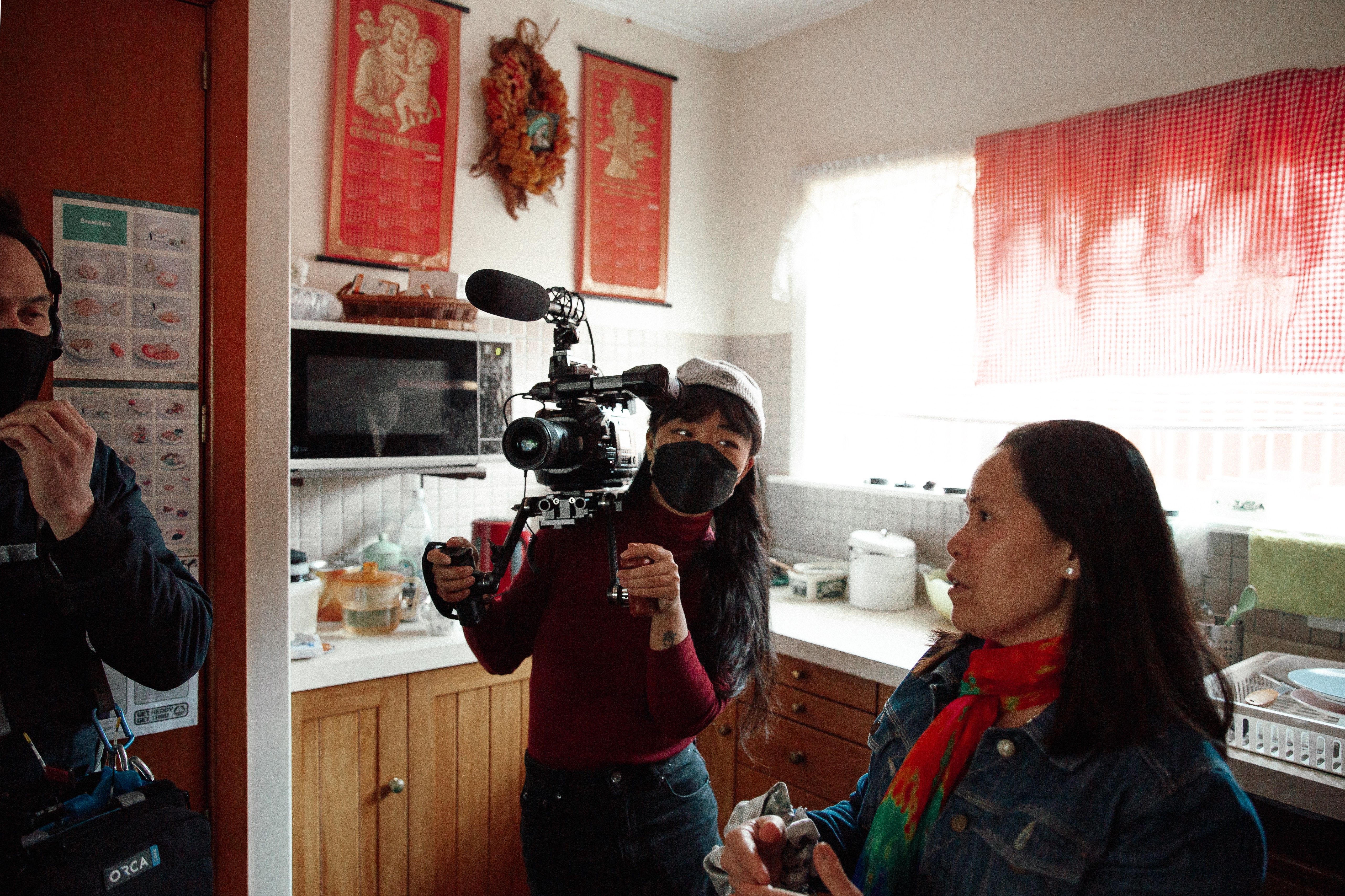 A woman in a mask holding a camera looking at another woman in a denim jacket