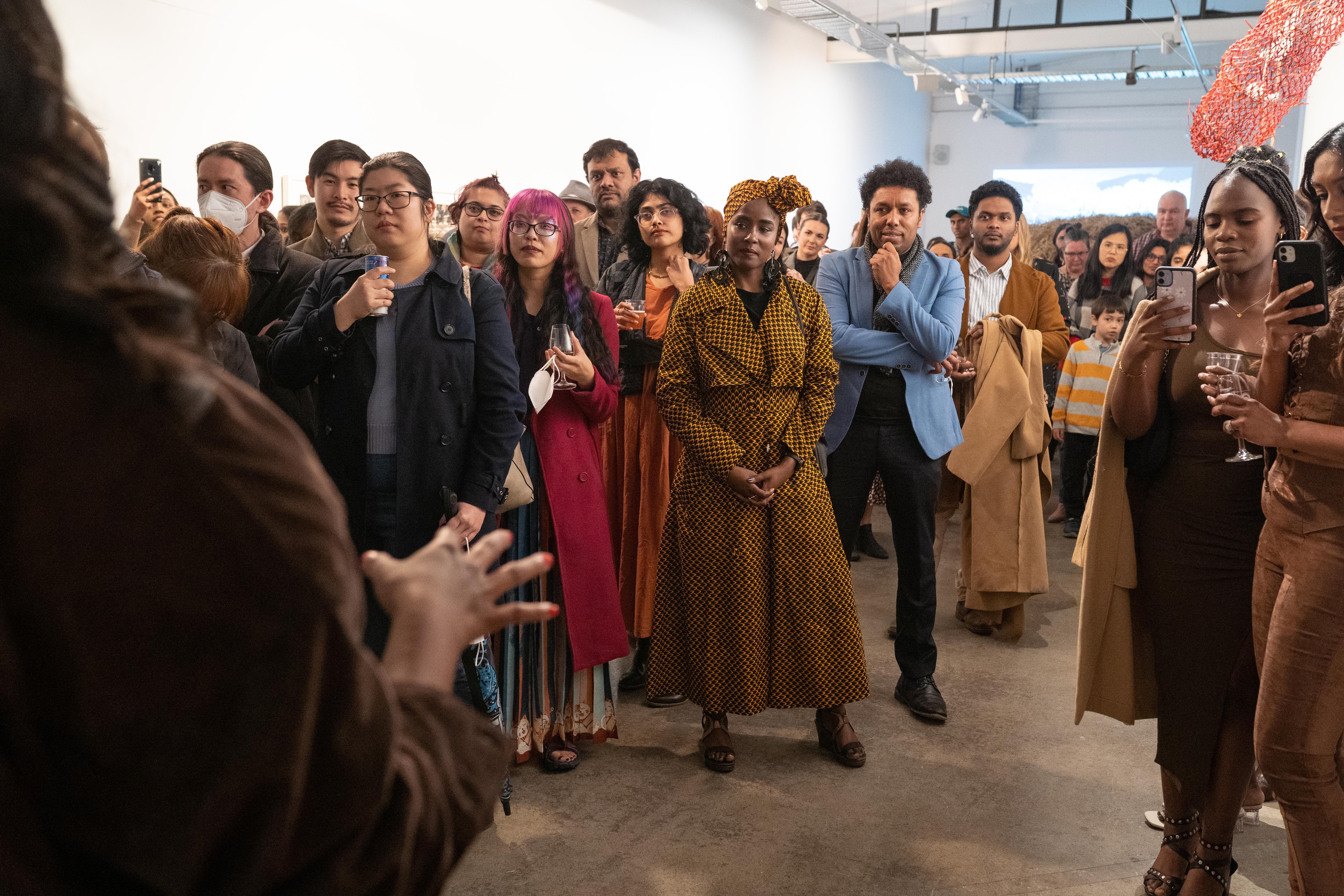 People standing in a crowd listening to a someone speaking