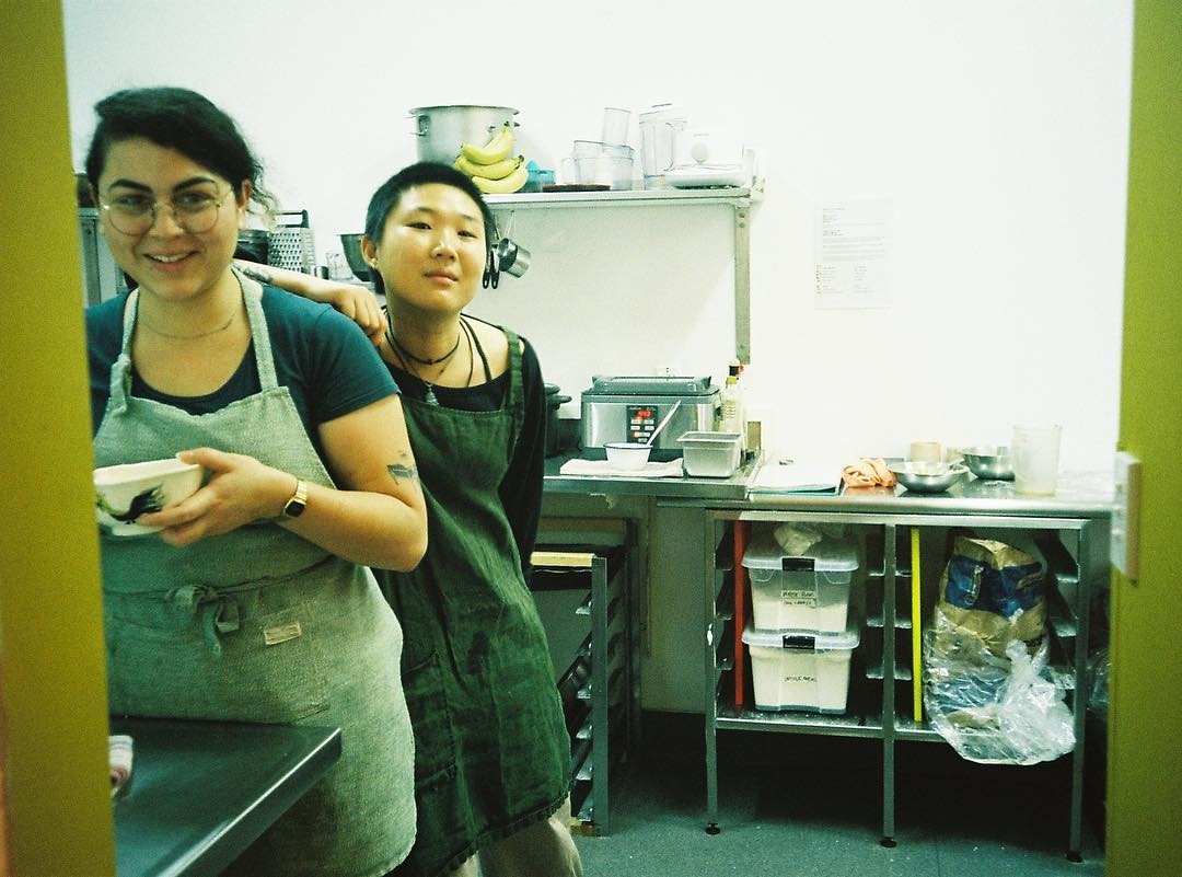 Two people with aprons on smiling at the camera