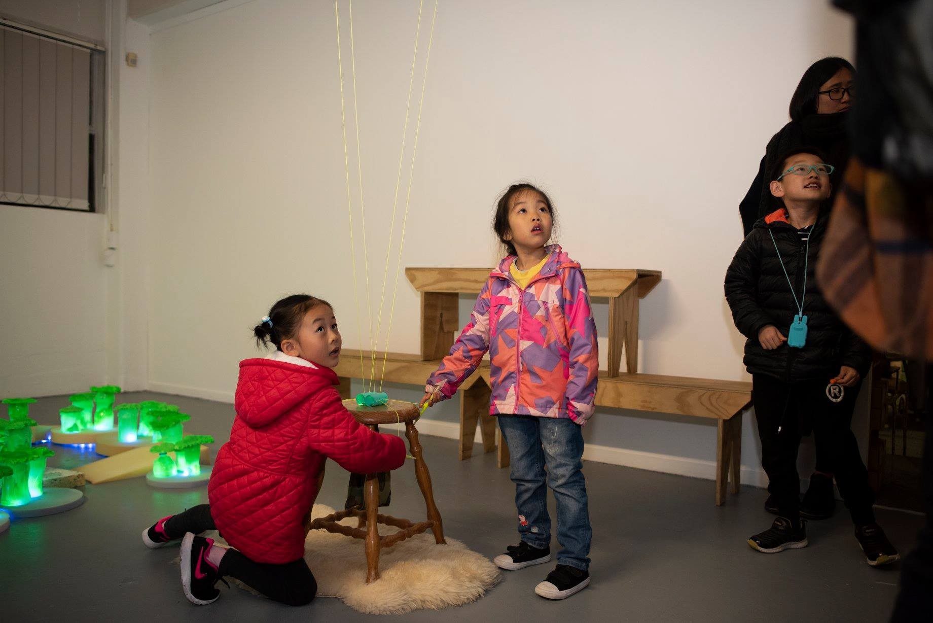 a little girl kneeing on the ground looking curious, playing with an installation