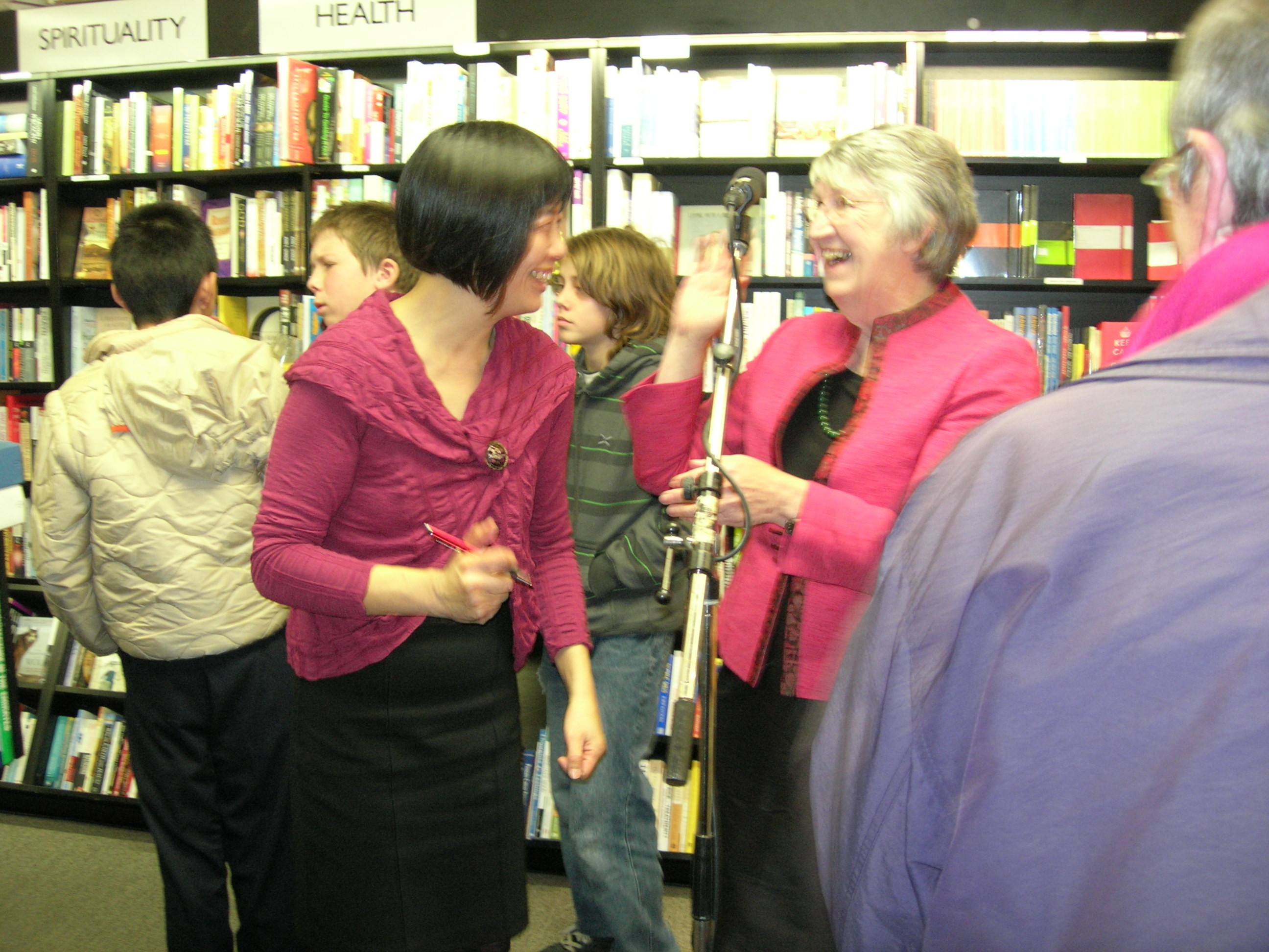 Two women with pink tops laughing with one another