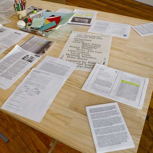 Photocopied articles and reading and writing materials scattered across a table.