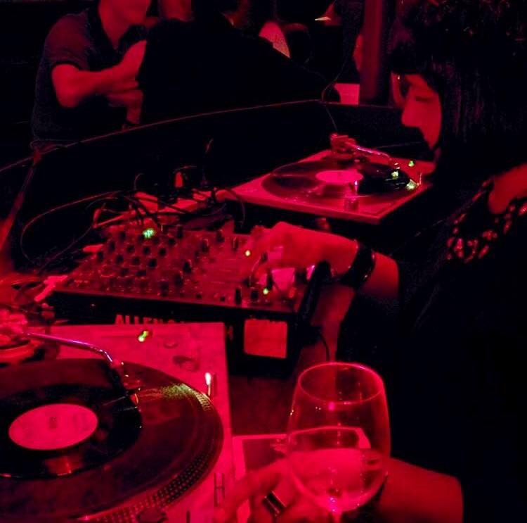A person playing record in a red-lit room