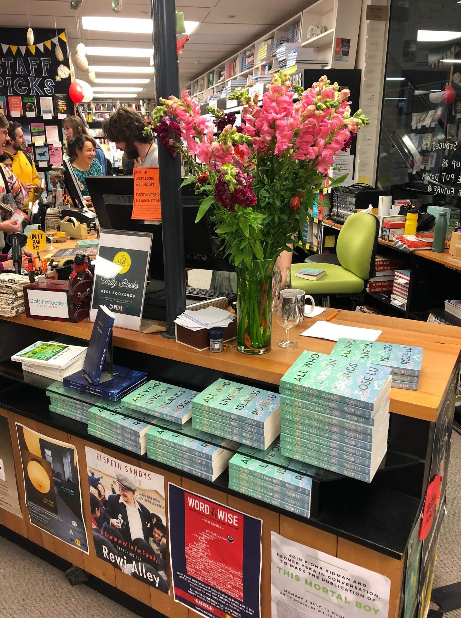 Stacks of the book 'All Who Live on Islands' at the counter of a book shop.