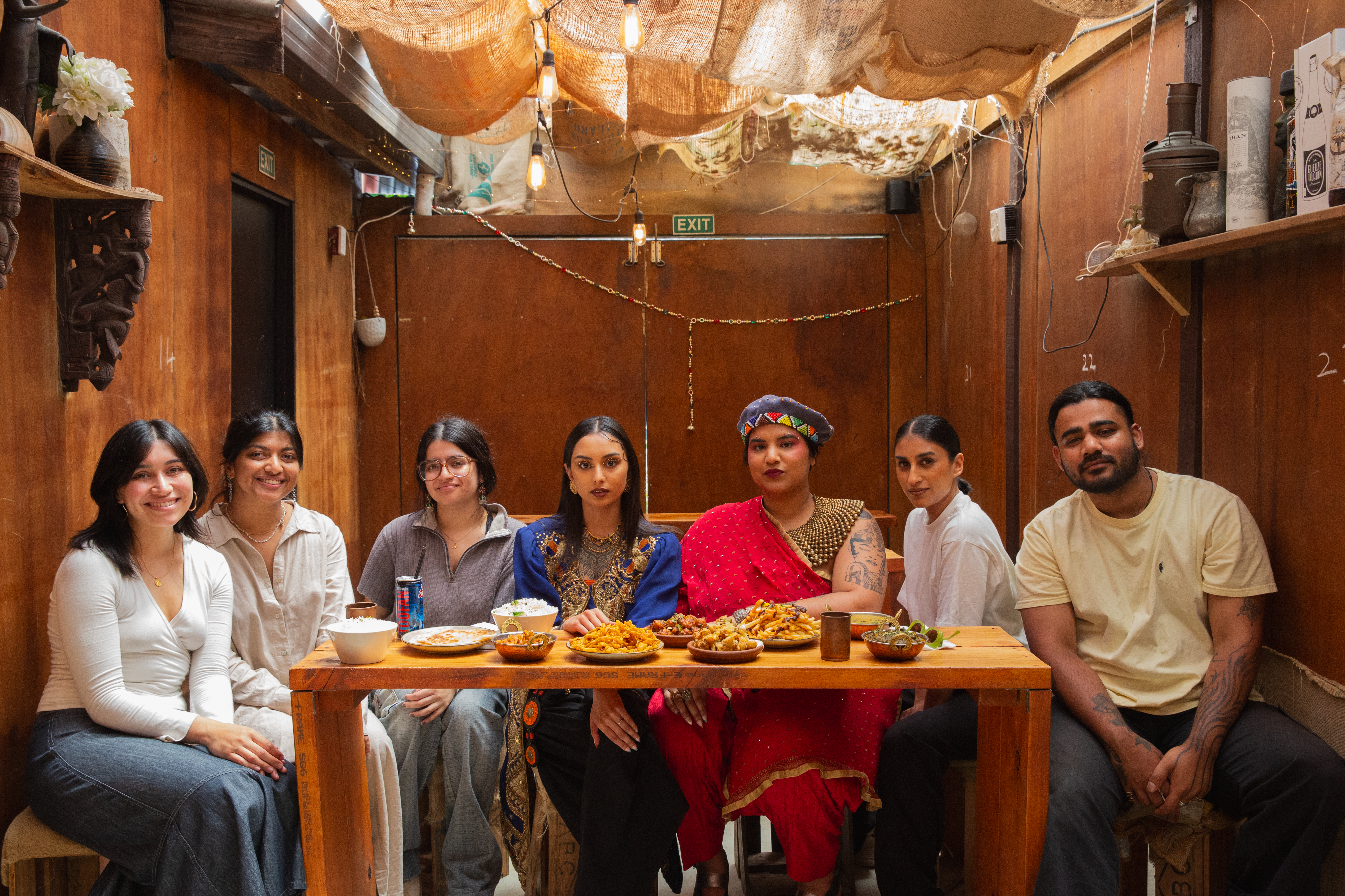 People looking at the camera sitting around a table with food