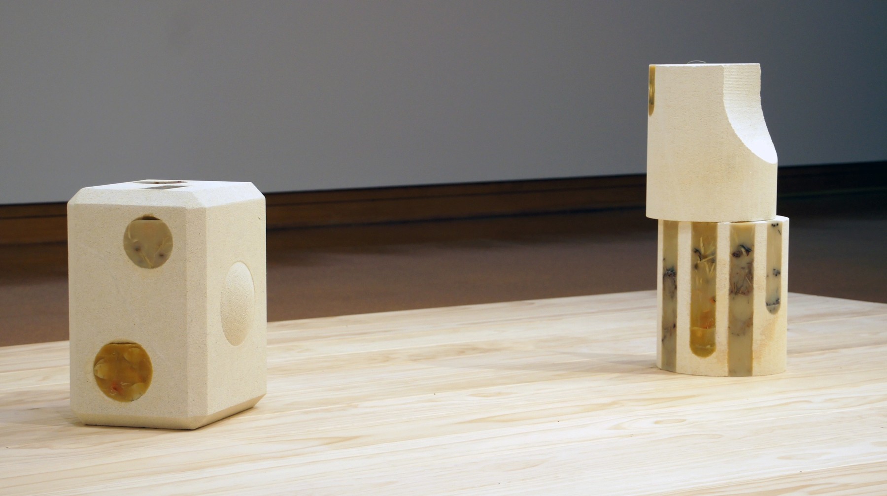 A white cast small speaker with objects embedded next two two round pillars stacked atop each other