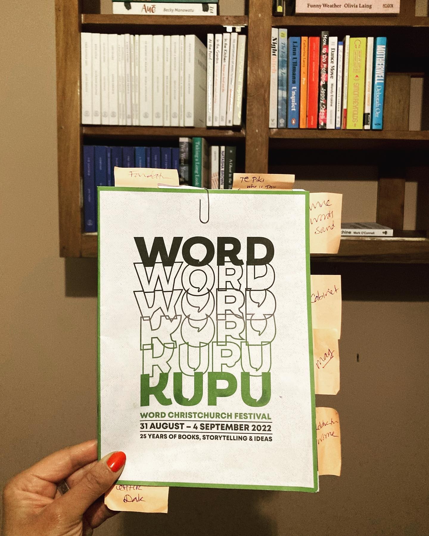 A hand holding up a printed festival programme