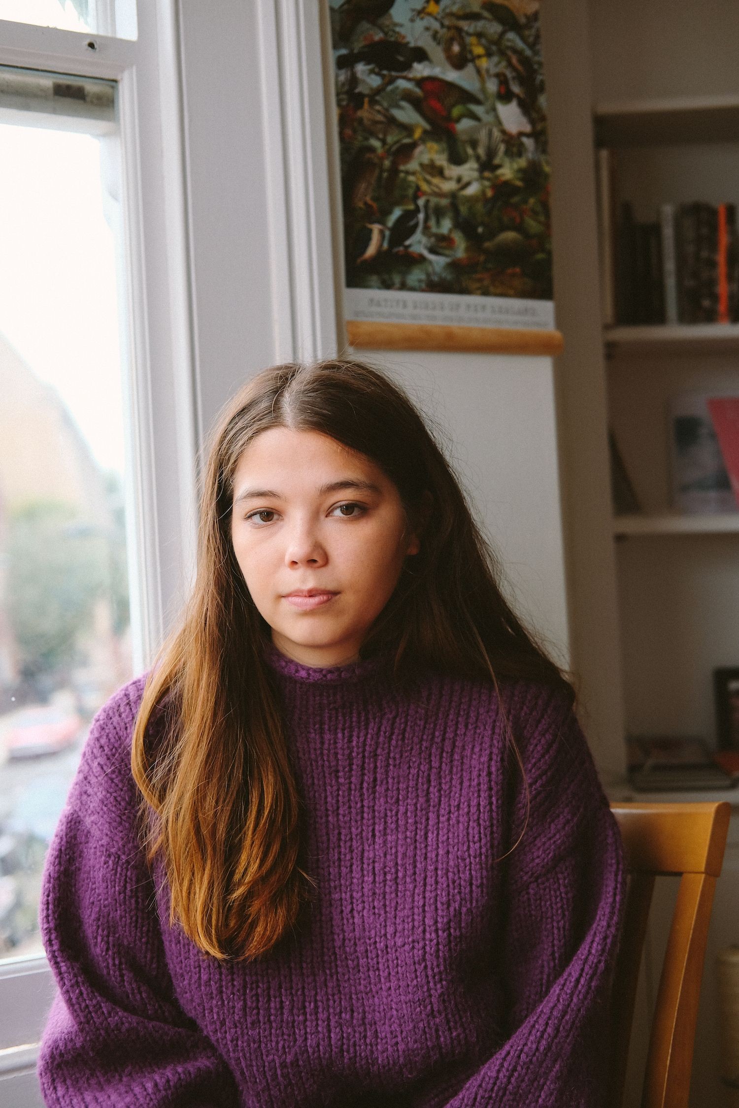 A portrait of a woman sitting in front of a window. 