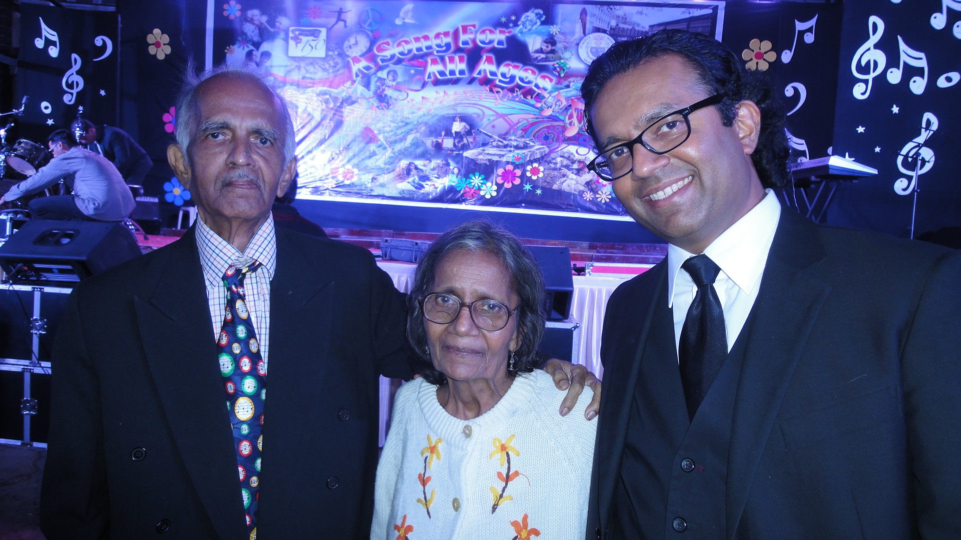 Three people standing together in front of a blue and purple background