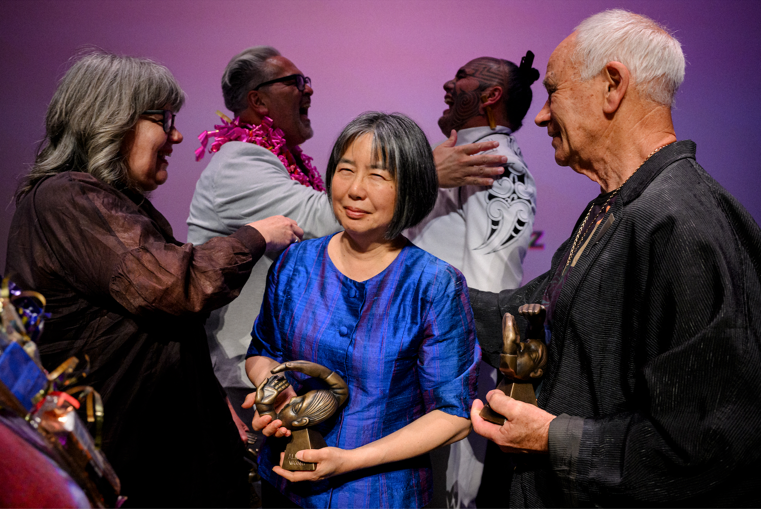 A group of people laughing and holding small statues