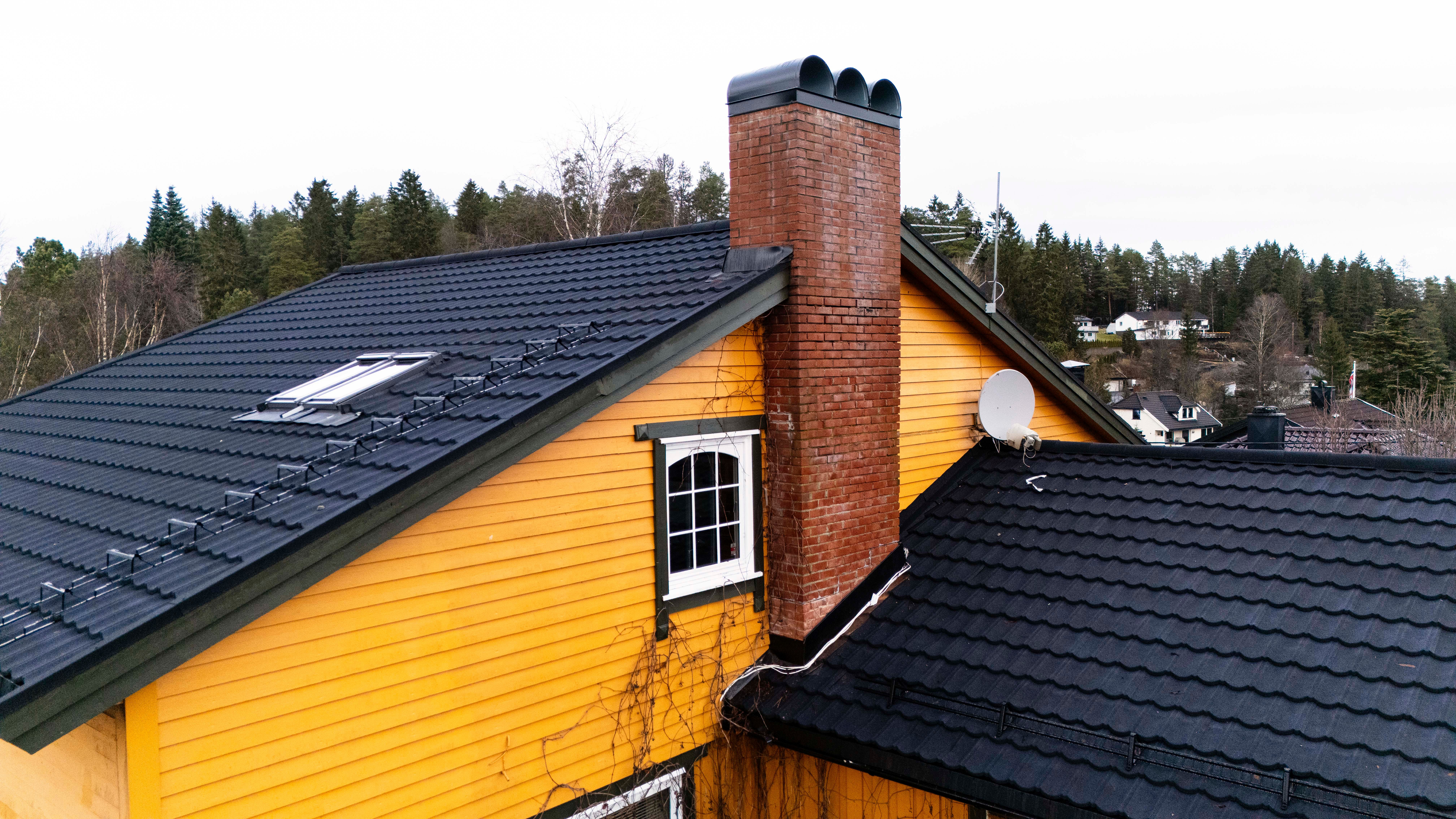 Nytt tak sett fra siden gult hus med grønne karmer og sorte taksten