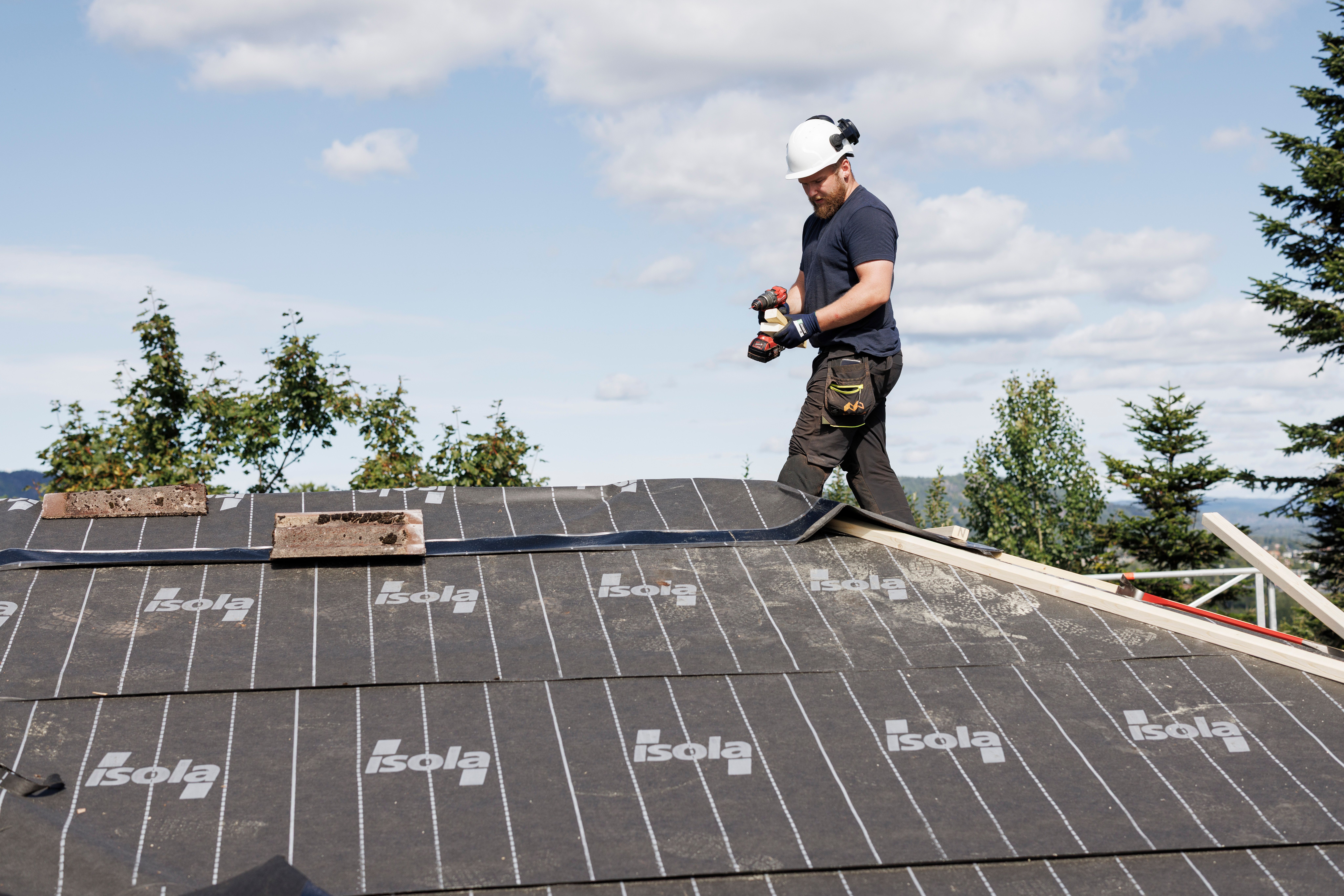 Tømrere som bytter tak på en enebolig med stillas rundt bygget