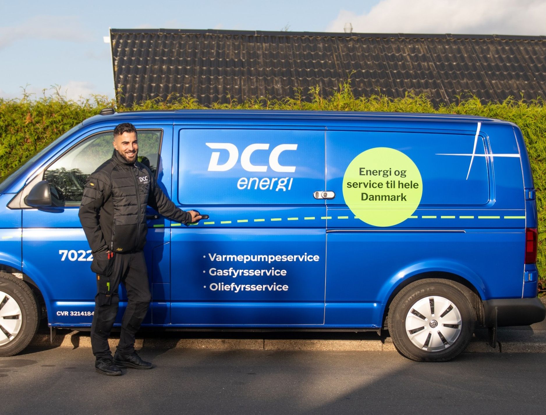 Servicemedarbeider foran en DCC Energi-bil parkert ved en bolig.