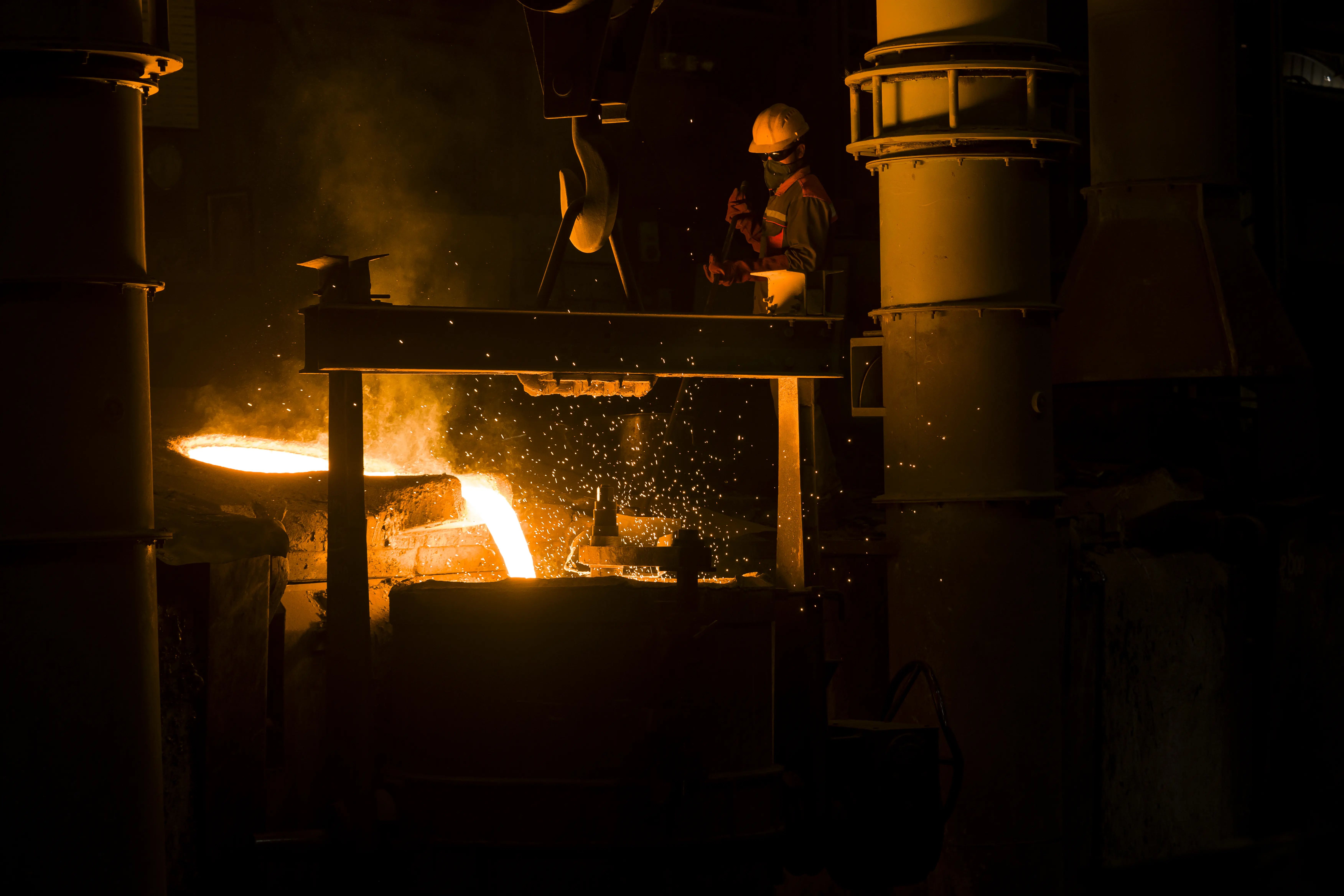 Operator observing induction furnace with molten metal in crucible