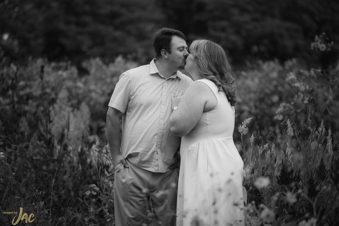 A couple kiss in a meadow of tall wildflowers