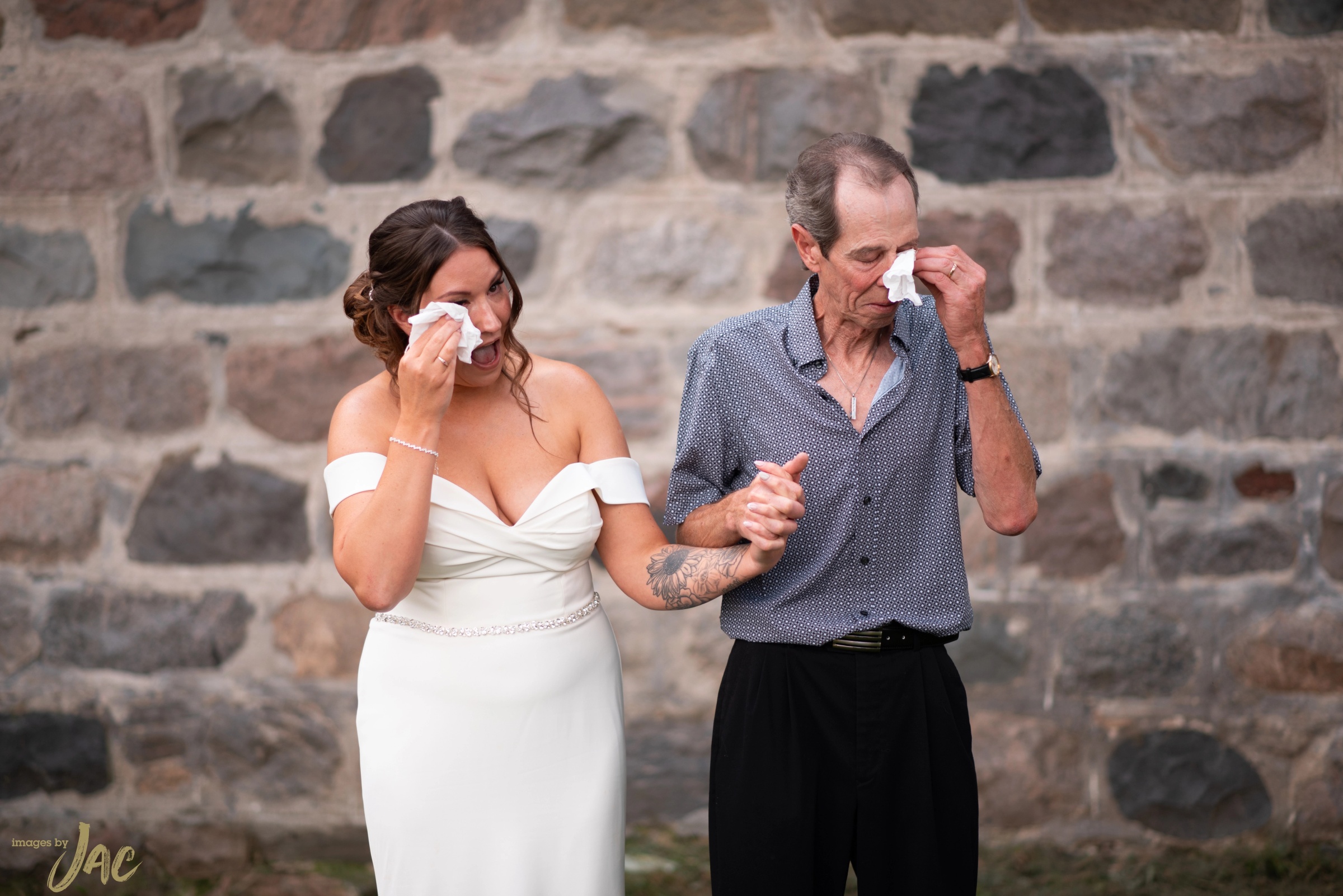 A bride and her father both wiping away tears