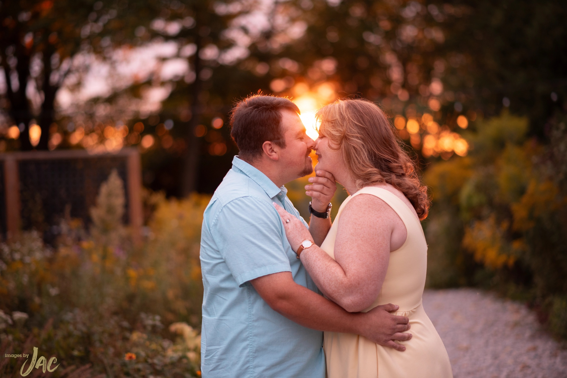 A couple touching foreheads as the sun sets behind them