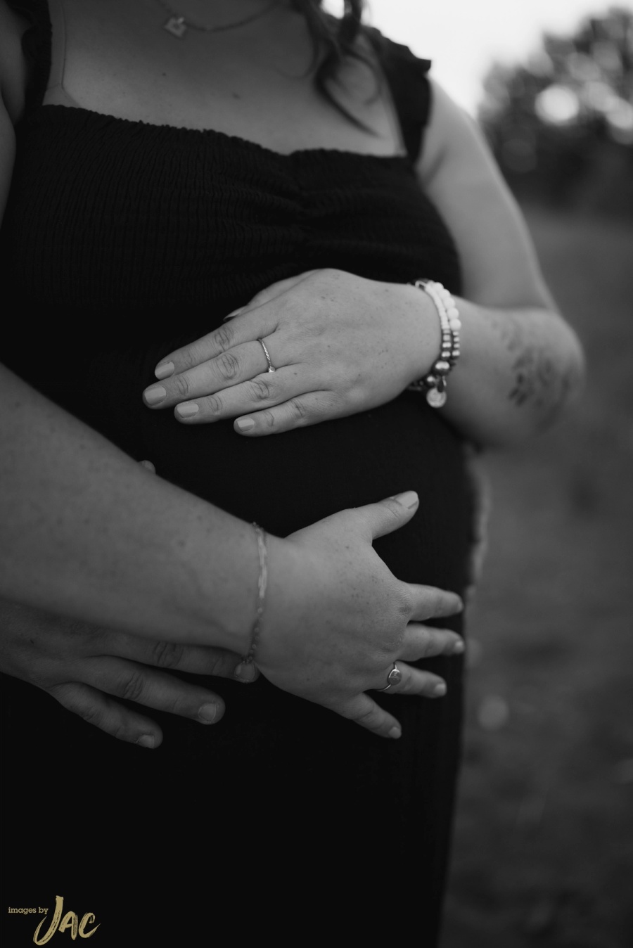 Two pairs of hands resting together on a pregnant belly