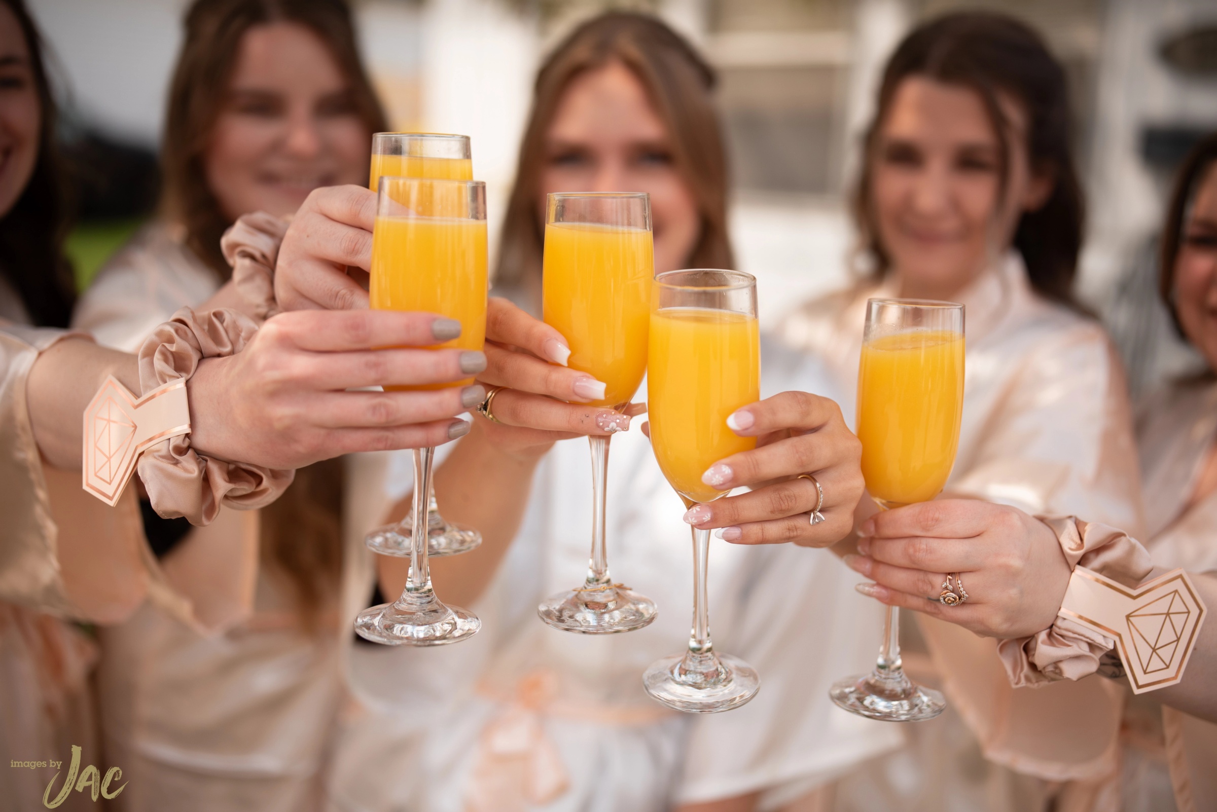 Bridesmaids in matching robes raise their glasses in a toast