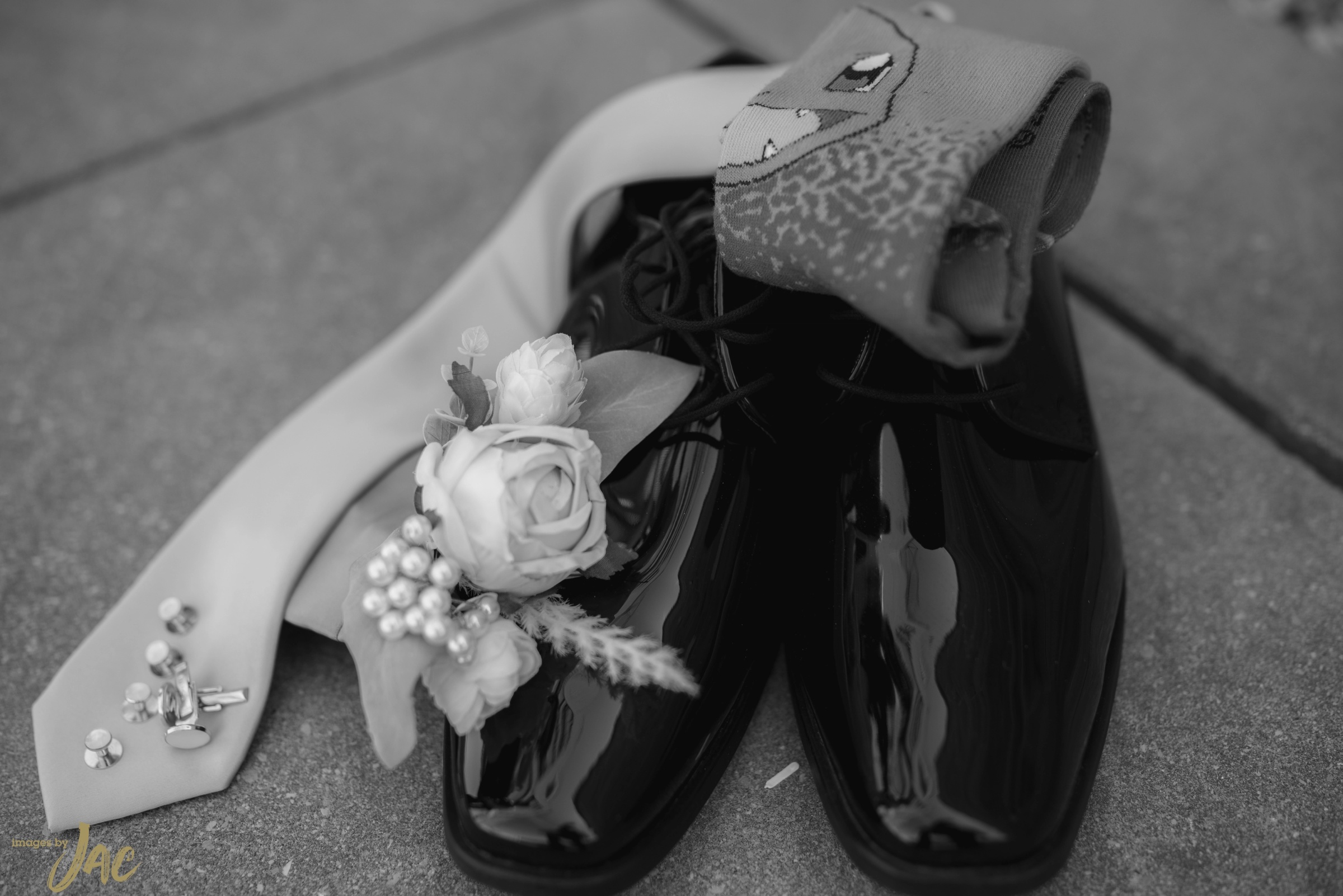 A tie, a rose boutonniere and polished shoes arranged on a stone step