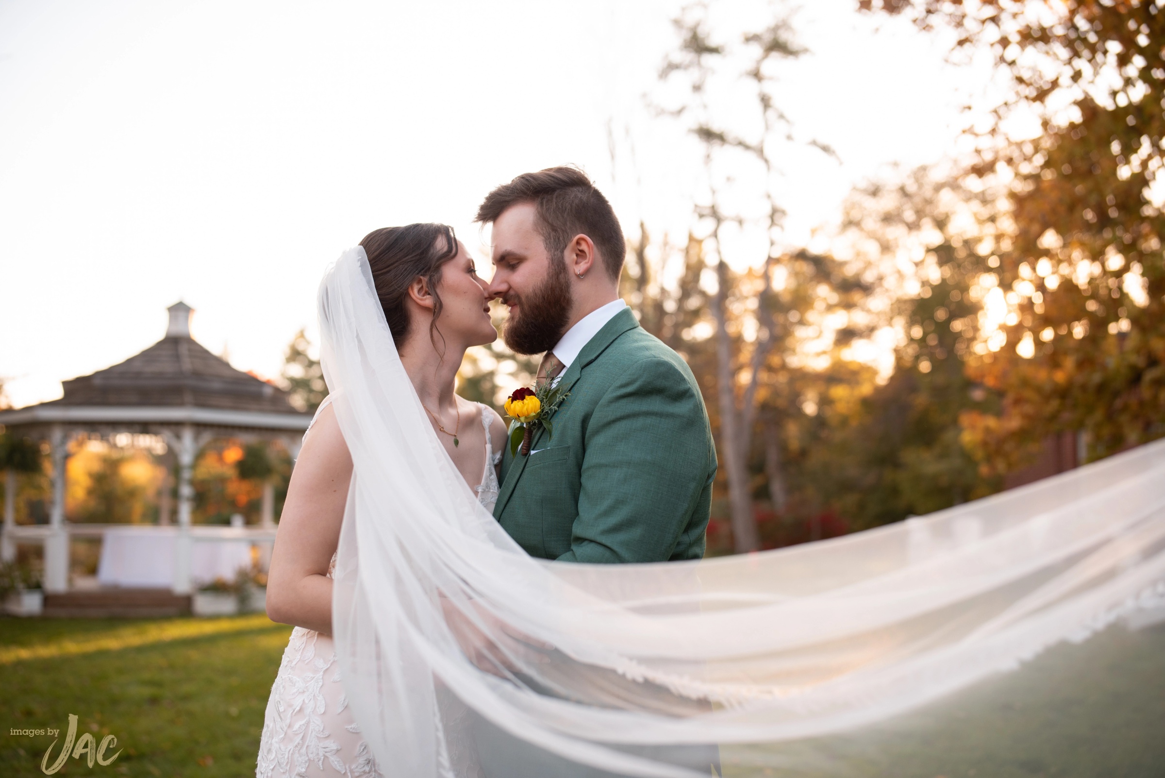 A bride and groom at sunset, her veil lifting behind them