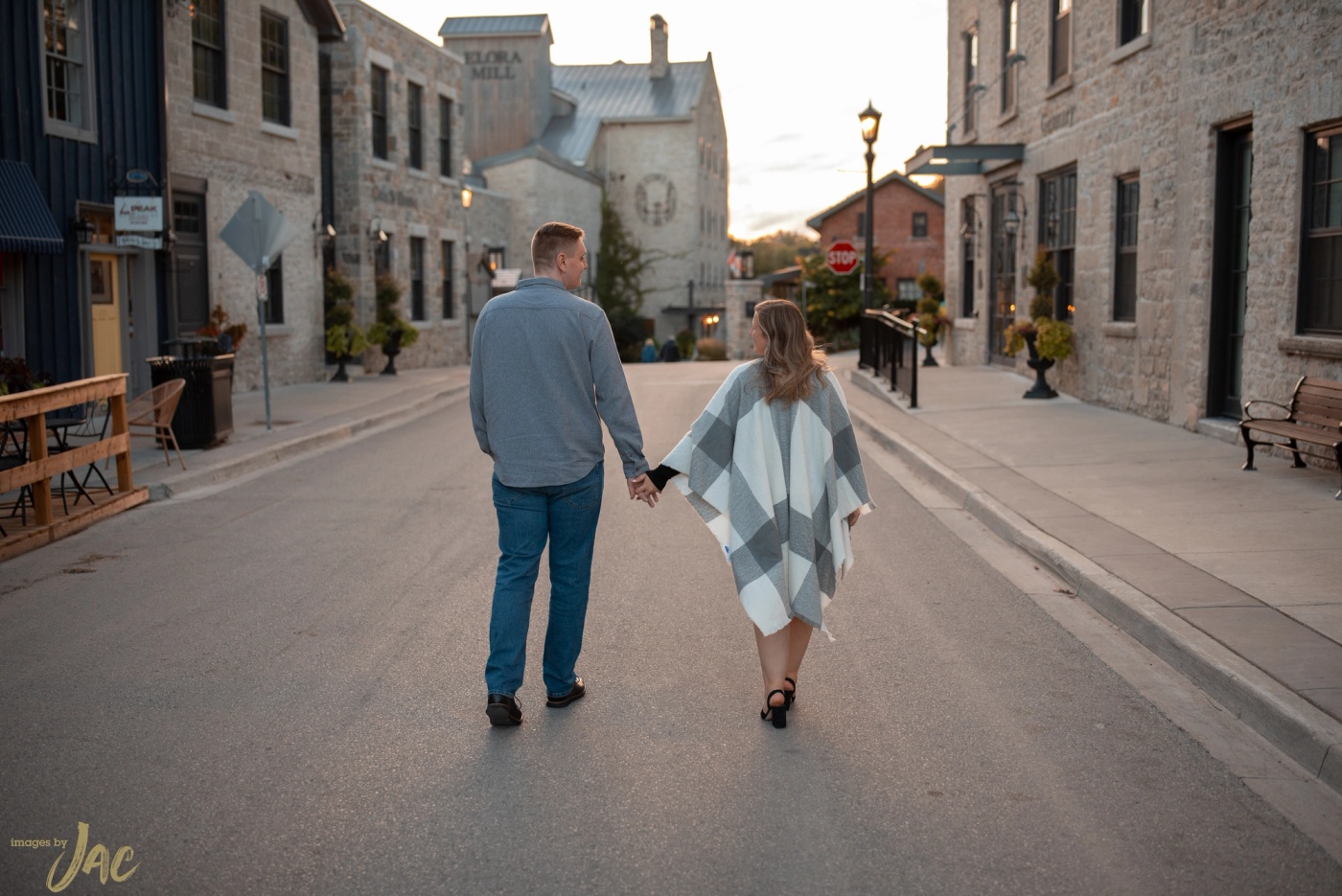A couple walk away hand in hand down a quiet main street