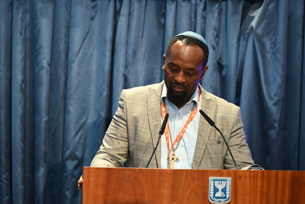 Wearing a kippah, a Jewish skullcap, Dennis Nthumbi addresses a forum in Israel aimed at whitewashing Israeli crimes of apartheid and genocide of Palestinians