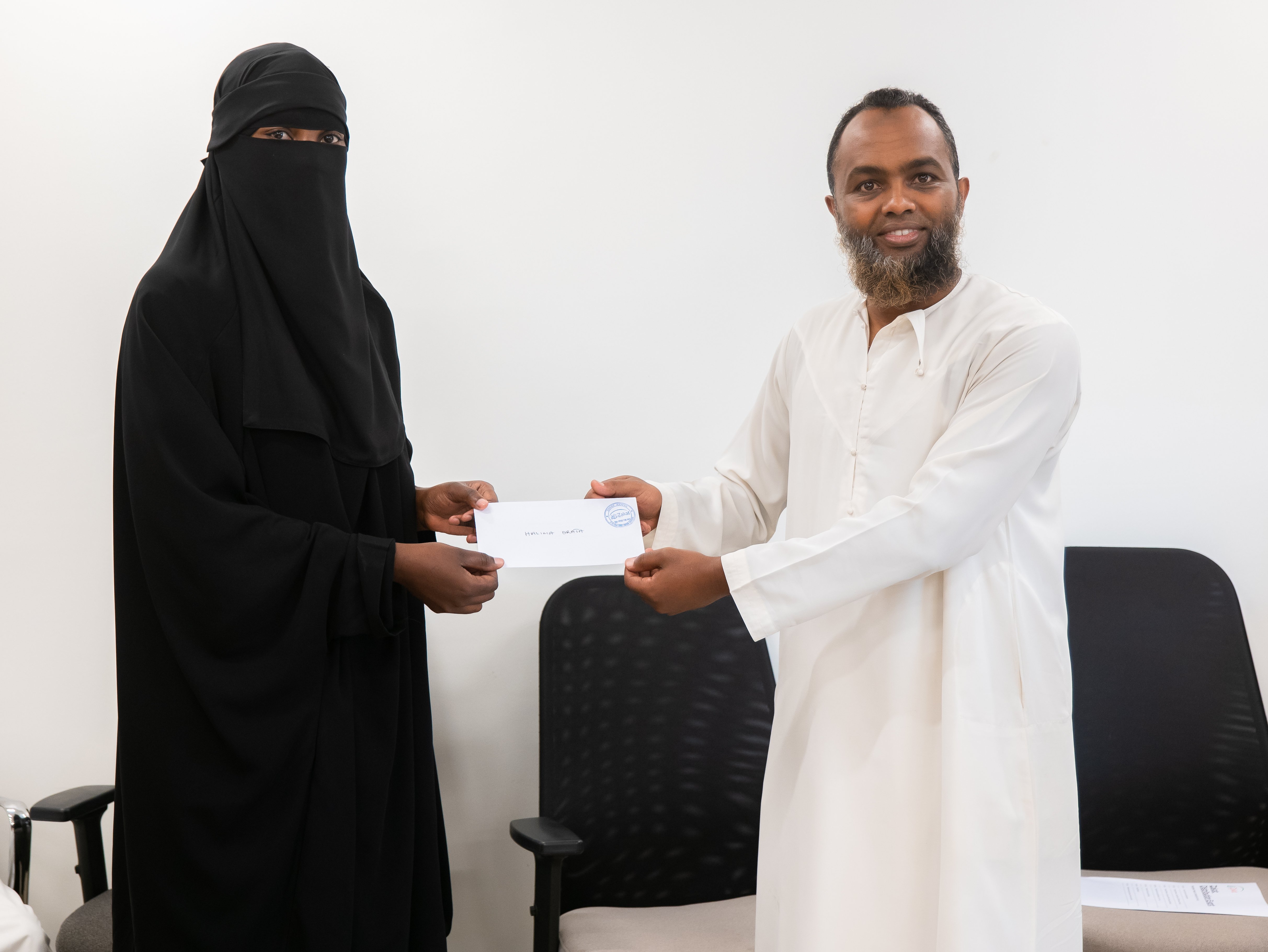 Ali Sharrif from Zakat Kenya hands over a cheque for Zakat to a beneficiary