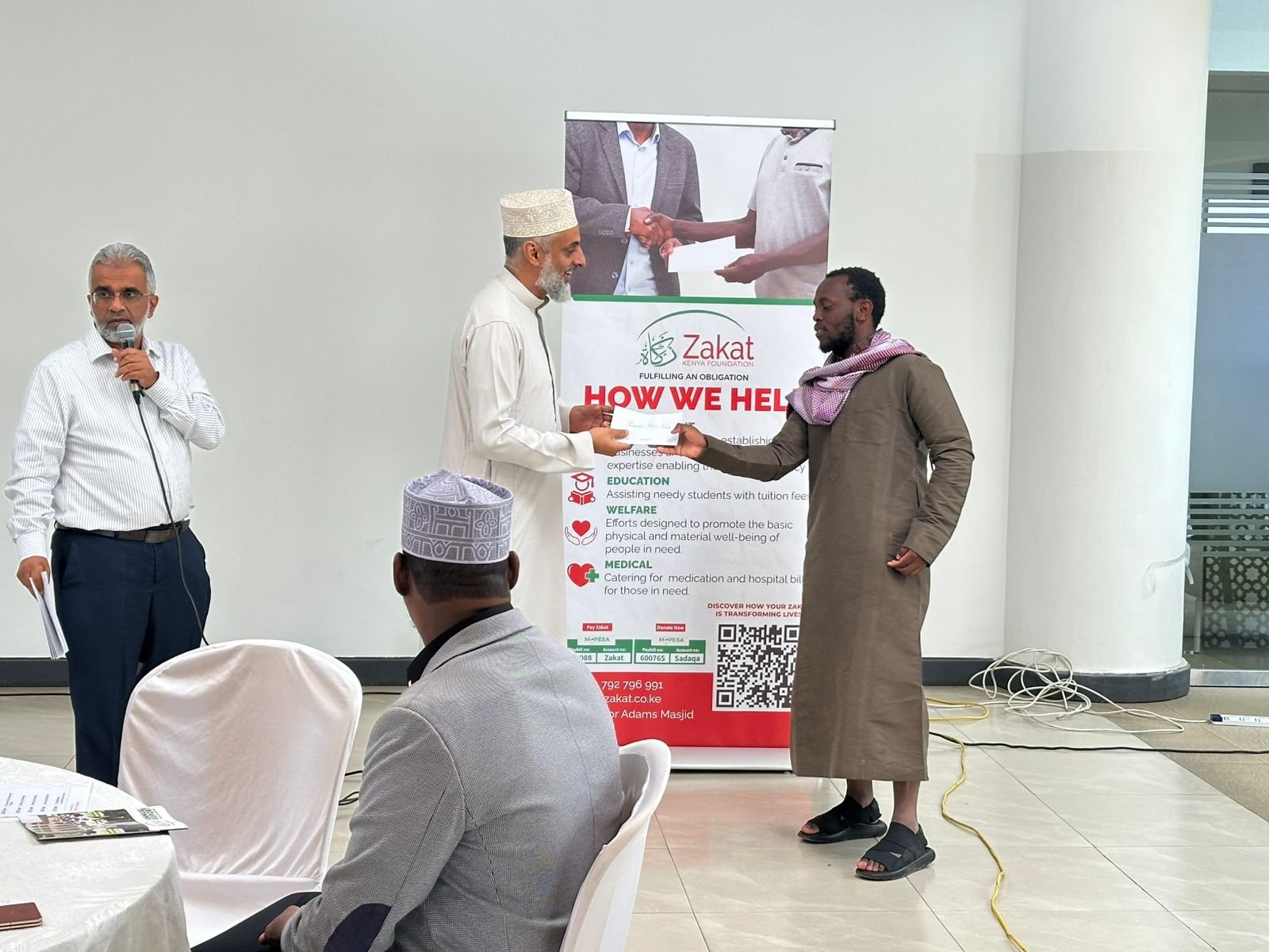 Zakat Kenya official Abubakar Bajaber presents a cheque to one of the beneficiaries during the organisation's empowerment fund distribution exercise. On the left is Zakat Kenya Chief Executive Officer Munawer Esmail.