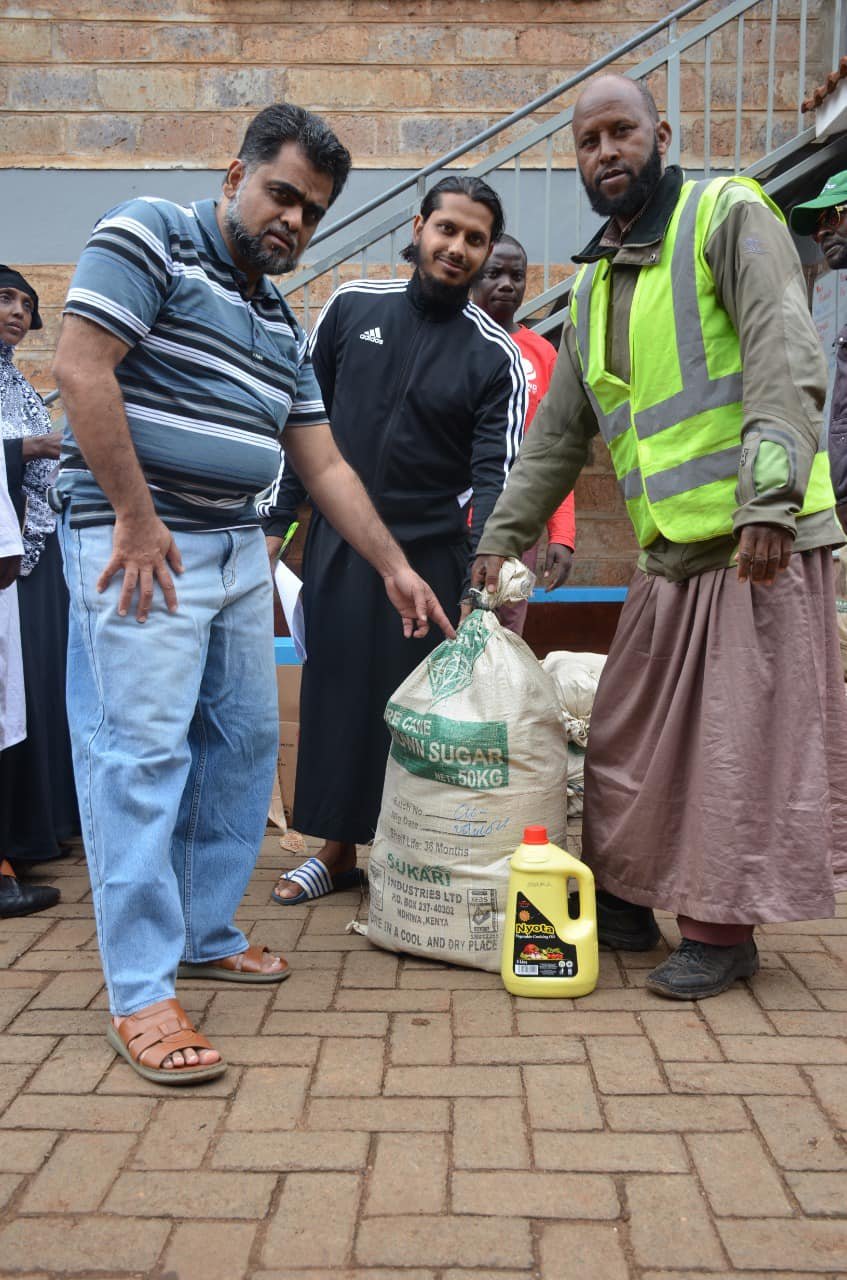 Jamia Mosque's Finance Officer Abubakar Nazir with the Imam of Parklands Mosque Sheikh Abdulrahman Ishaq presents a food pack to a beneficiary from Deep Sea slums in Parklands during a past Iftar distribution exercise