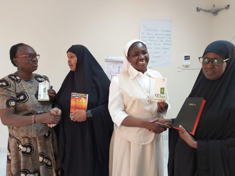 Muslim and Catholic women exchange copies of the Bible and the Quran during an interfaith forum to promote harmonious relationship
