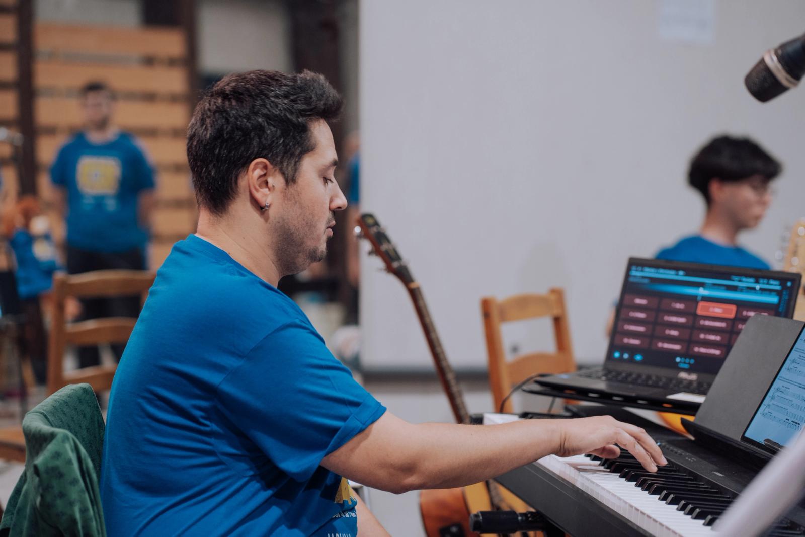 Profesor realizando un calentamiento vocal a los alumnos tocando el piano