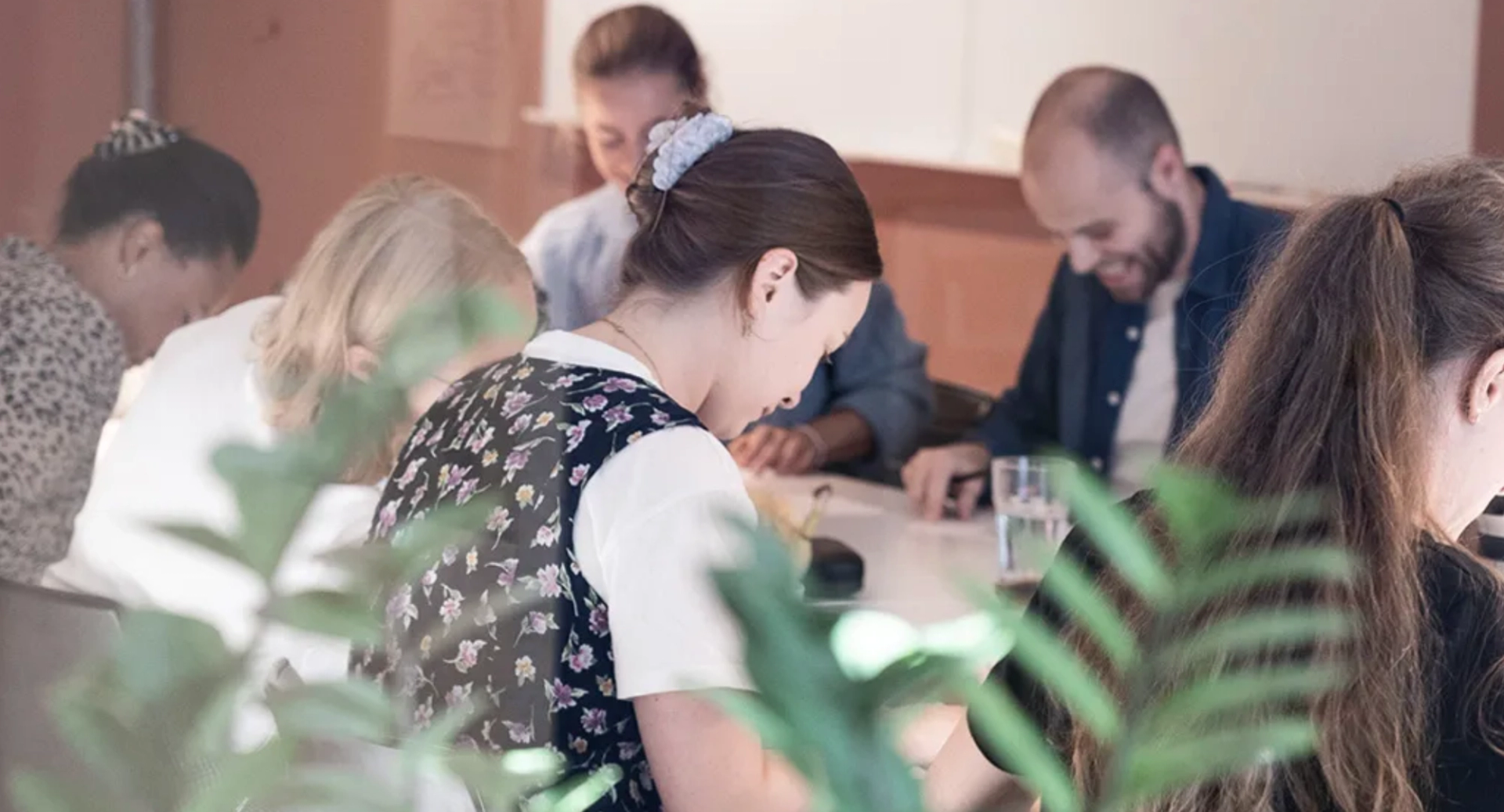 Folk samlet rundt et bord, jobber og ler.