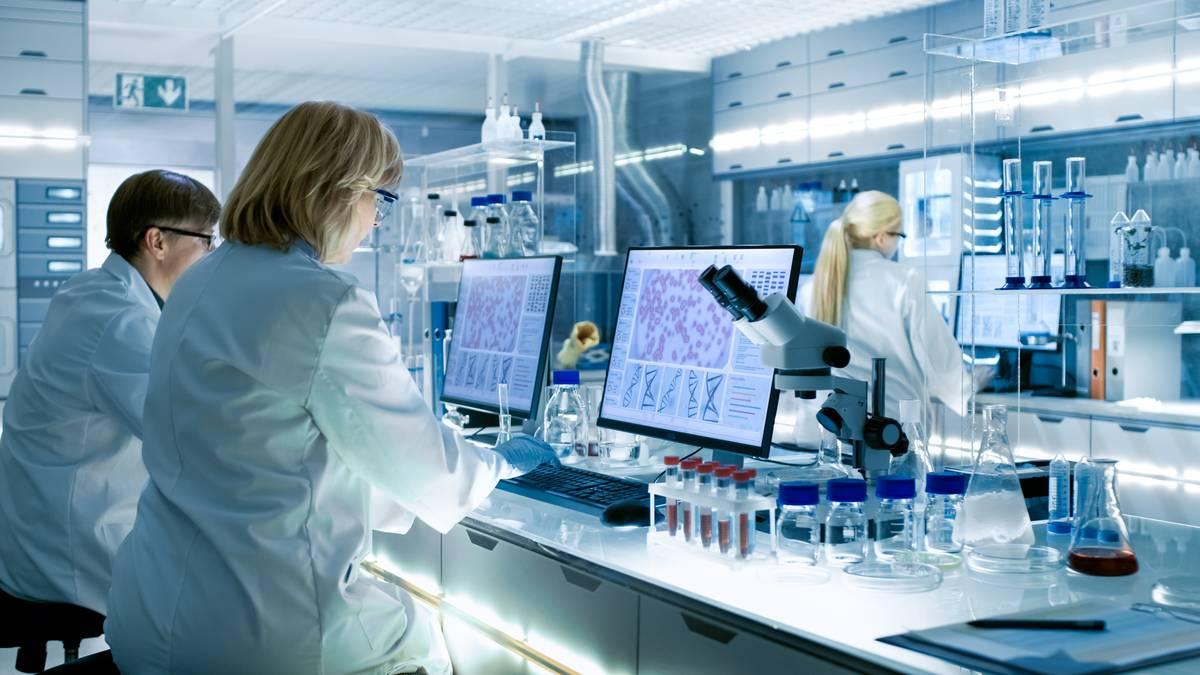 Forskere i laboratorier bruker datamaskiner og utstyr for å analysere data, med reagensrør og kolber på benken.